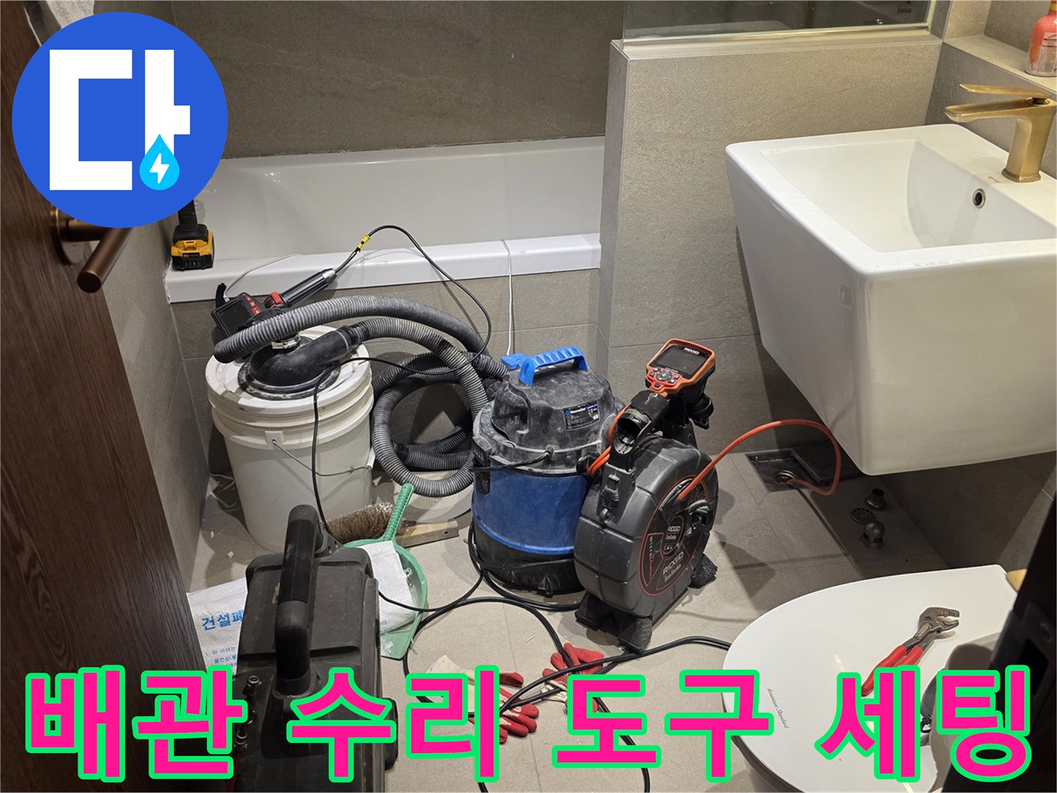 욕실 바닥에 배치된 배관 청소용 장비와 각종 핸드툴