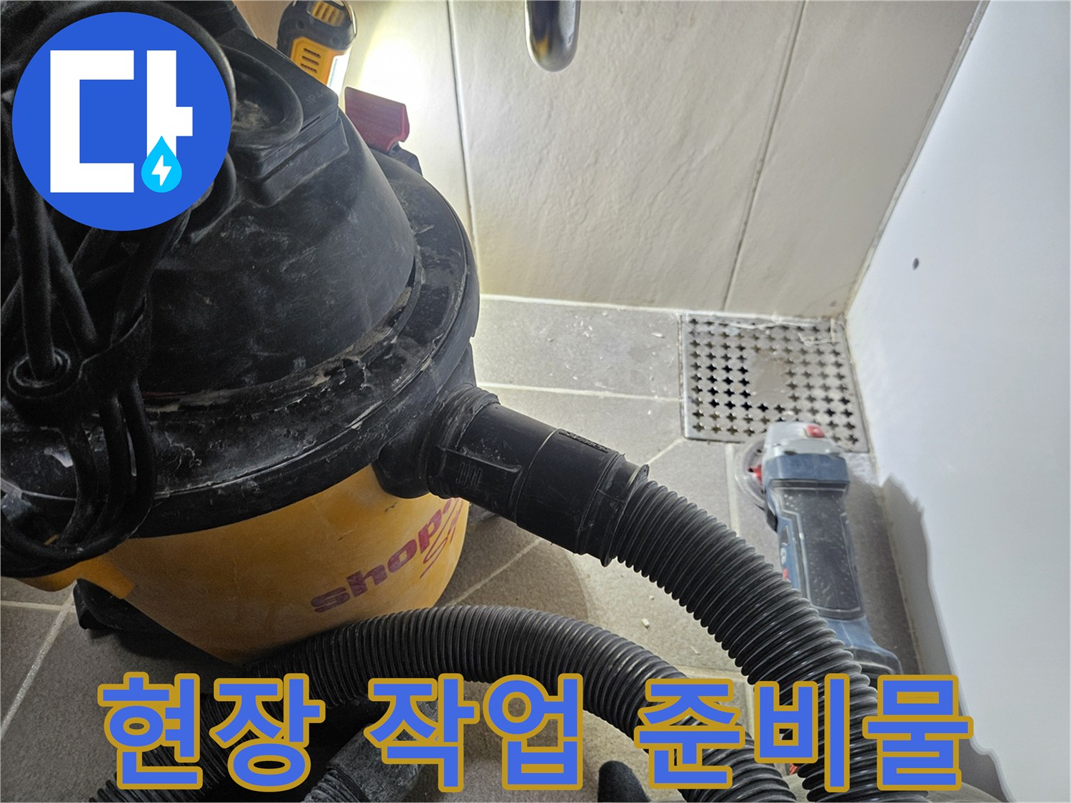 바닥 타일 위 설치된 산업용 청소기 호스와 전동 공구 세트