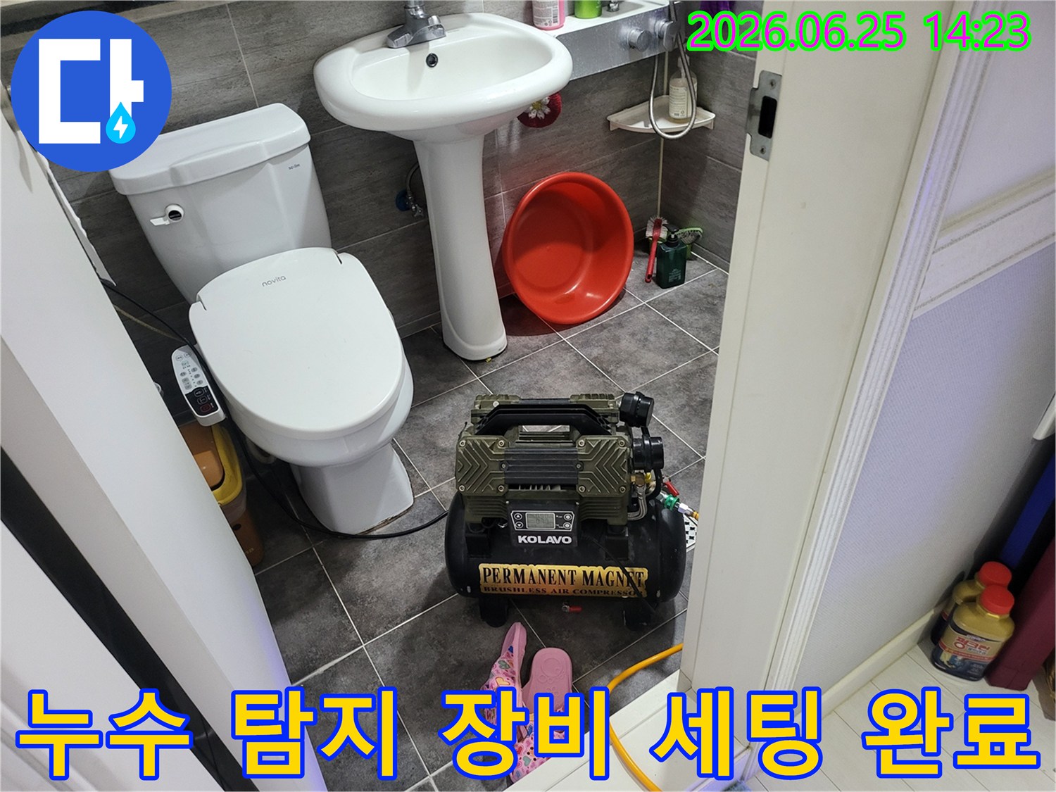 변기와 세면대 옆에 놓인-누수 탐지용 콤프레셔 장비가-작동 대기 중인 욕실 풍경