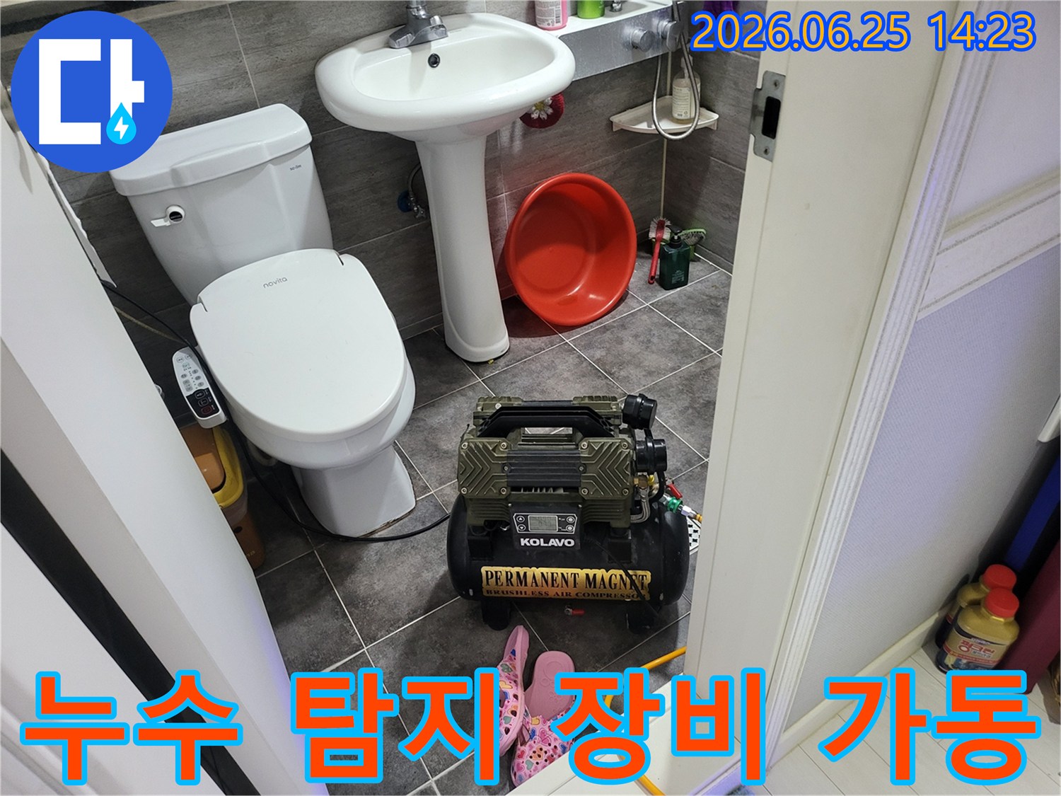 변기와 세면대 옆에 놓인-누수 탐지용 콤프레셔 장비가-작동 대기 중인 욕실 풍경