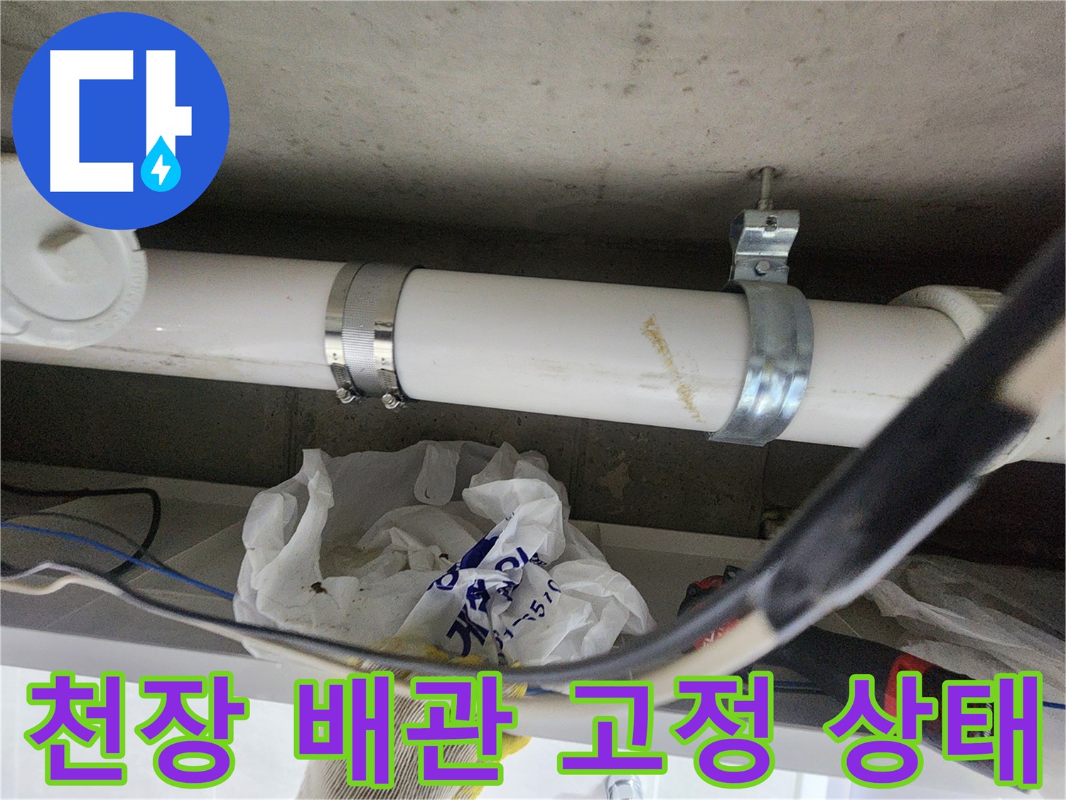천장에 설치된 흰색 배관과 금속 클램프의 모습입니다.