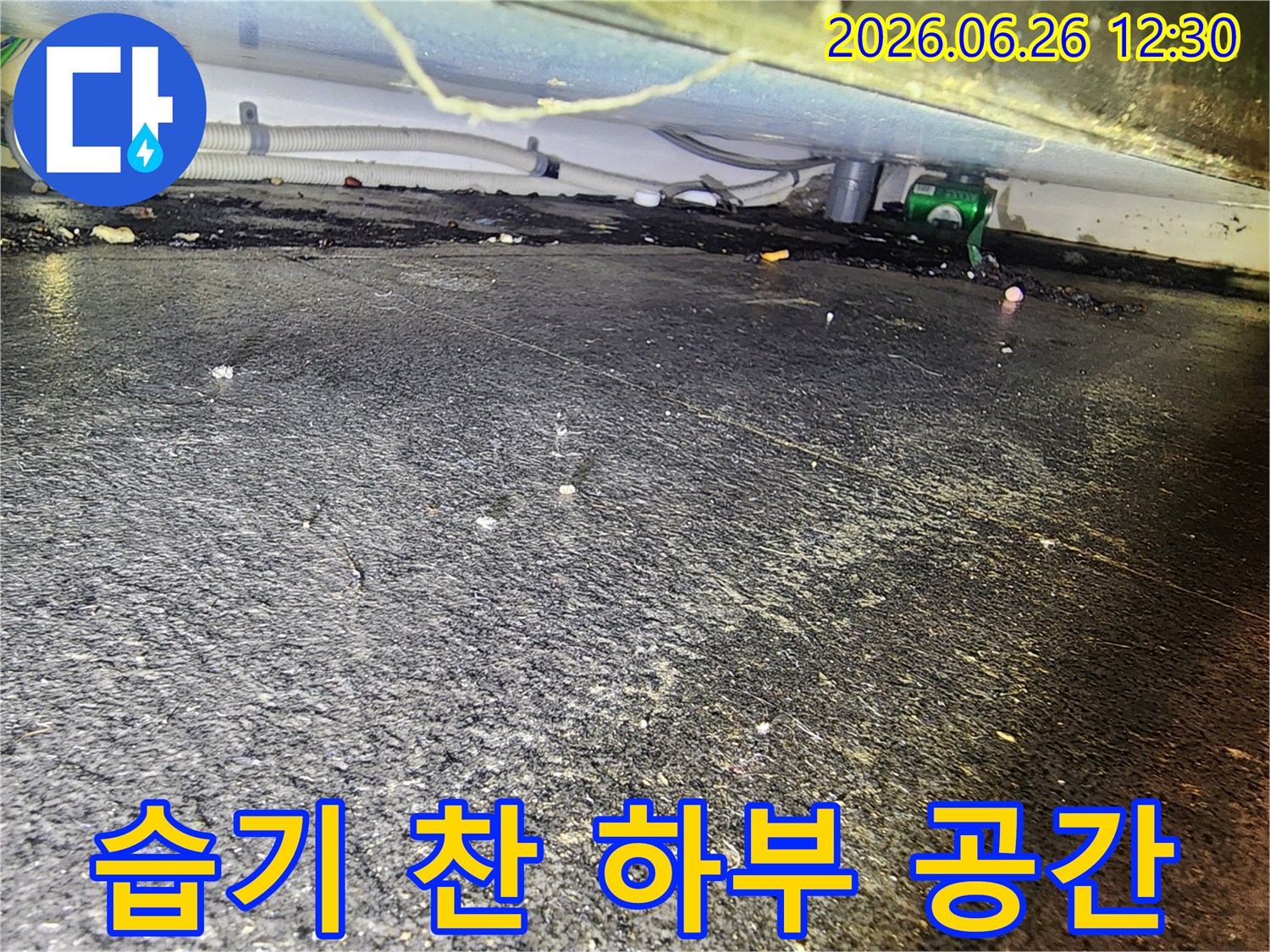 배관 연결부 근처-바닥에 고인 물과-흙먼지가 섞인-누수 현장을 촬영한 사진입니다