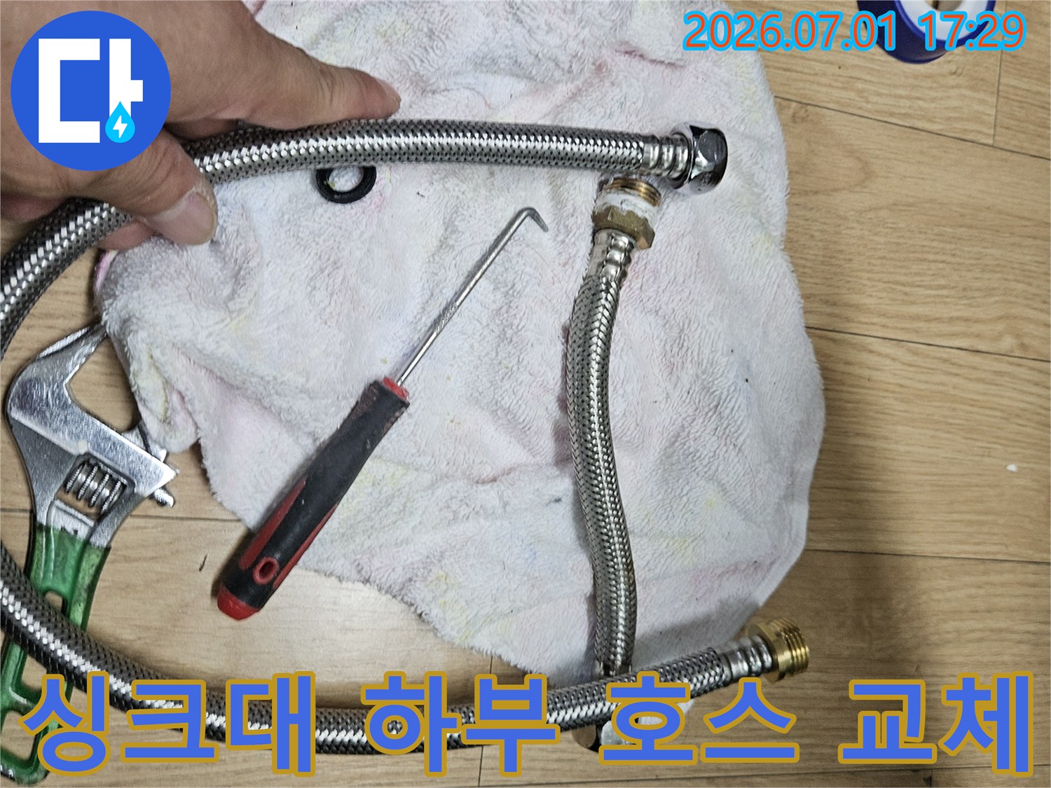 이 이미지는 빌라 싱크대 하부 배관 호스 교체를 위한-새로운 부품과 작업 도구를 보여주는 현장 사진입니다