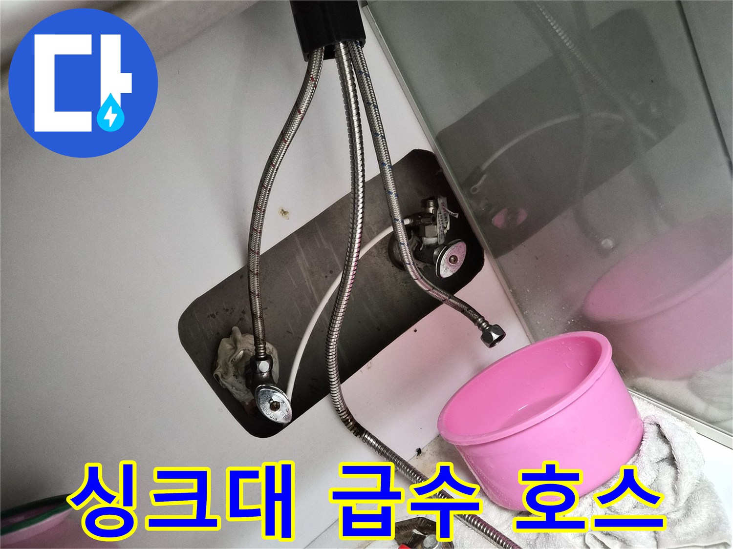 금속 소재의 유연한 배관과 밸브가 보이는 싱크대 하부장 내부