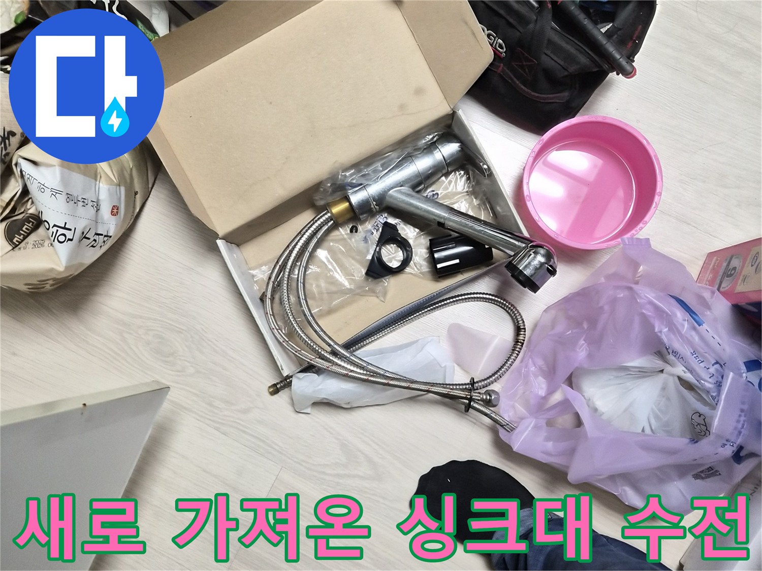 바닥에 놓여 있는 새 싱크대 수전 부품과 작업 도구들