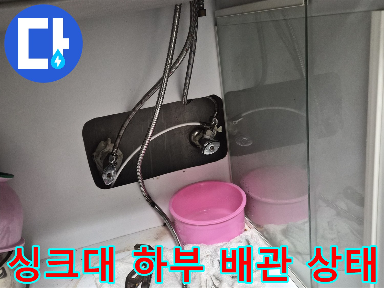 싱크대 하부장 내부에 보이는 금속 호스와 밸브 장치들