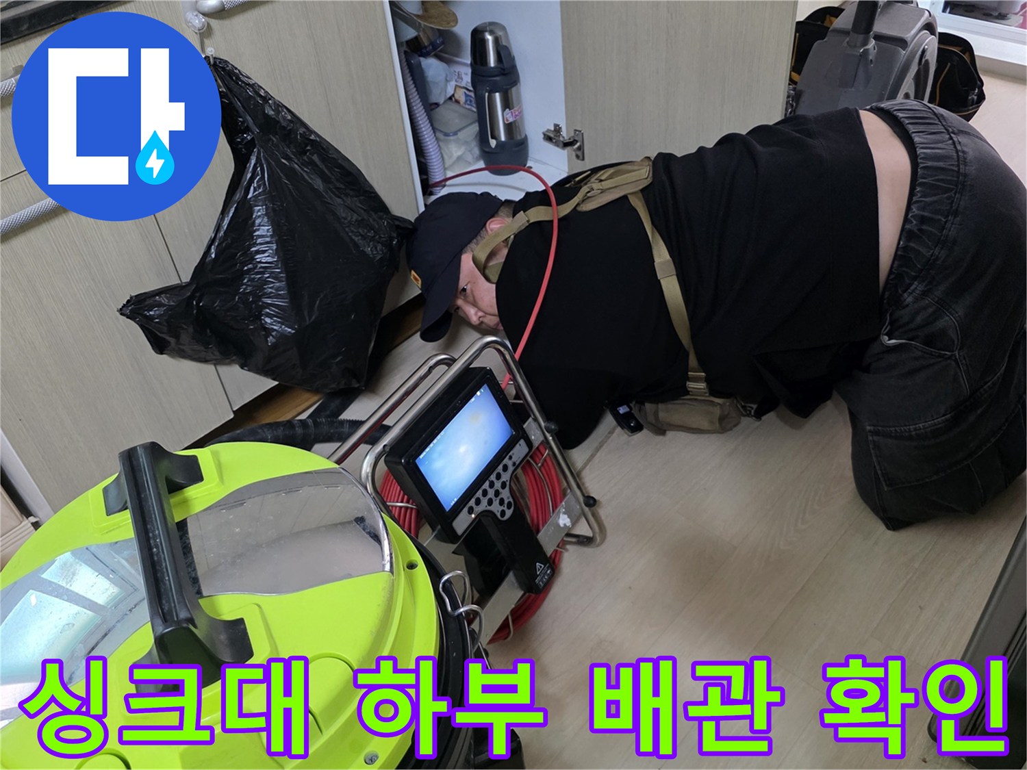 싱크대 아래쪽 좁은 공간에서 배수관의 누수 여부를 정밀하게 체크하고 있습니다.