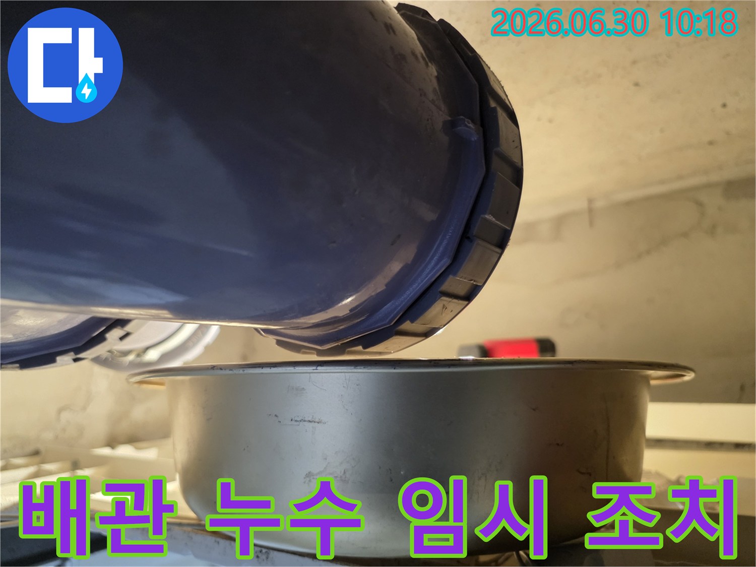 누수-현장에서-배관의-연결-부위에서-물이-새는-것을-발견하고-아래에-물받이를-놓아-임시로-물을-받고-있는-모습입니다.