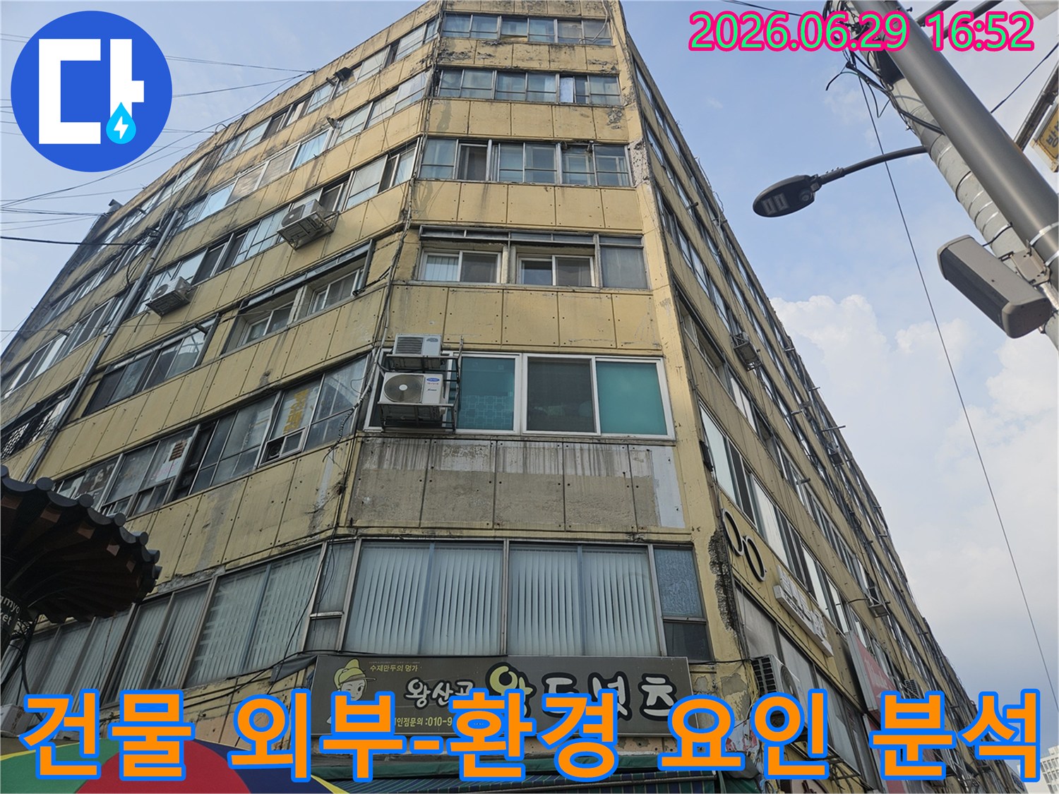 오래된 상가 건물의-외벽과-주변 환경을-종합적으로-분석하며-누수 원인을-찾는-전문가의-모습