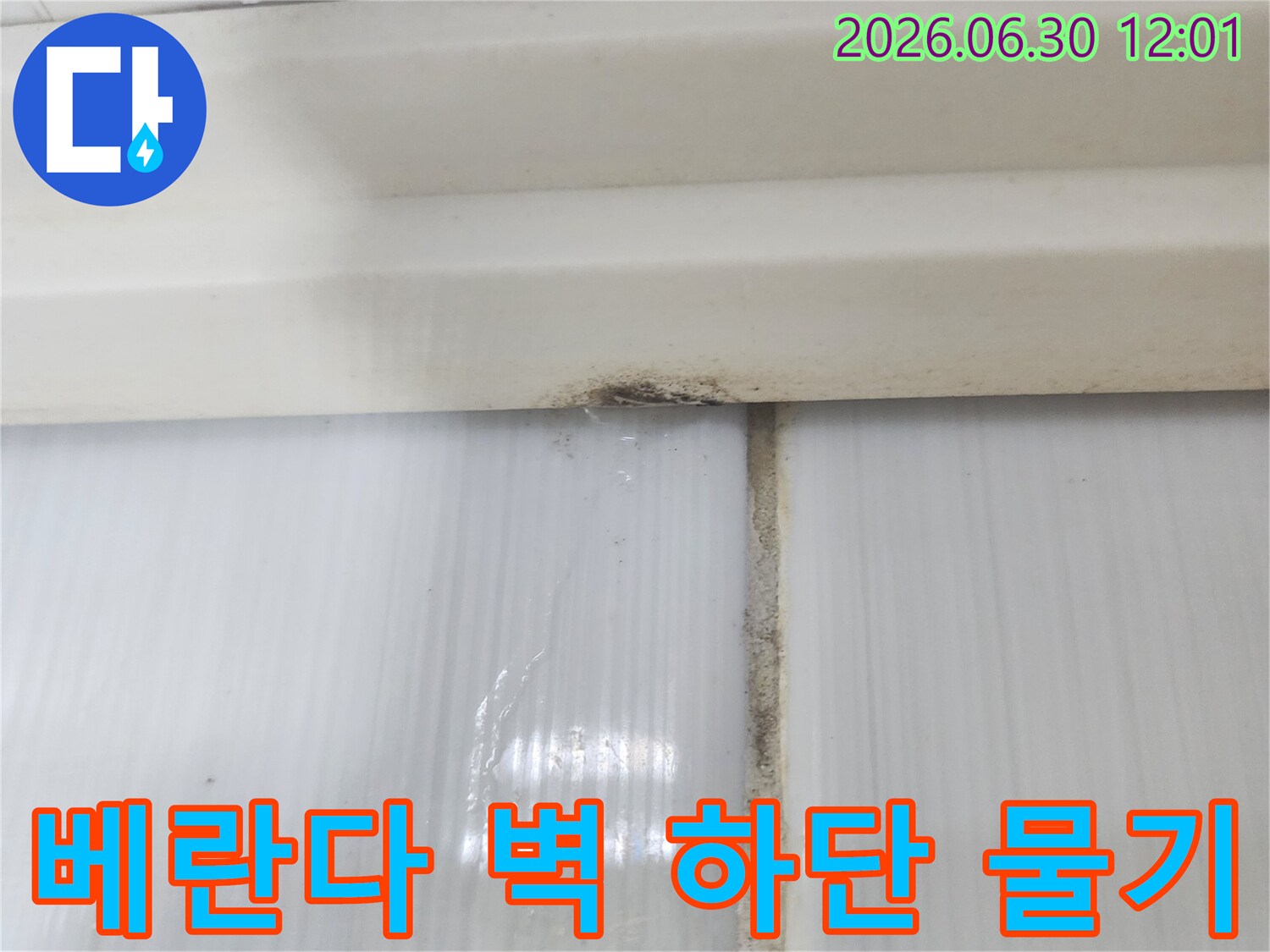 아파트 베란다 벽면 하단에서 물기가 확인되고 오염된-누수 현장의 진행 상황을 보여줍니다