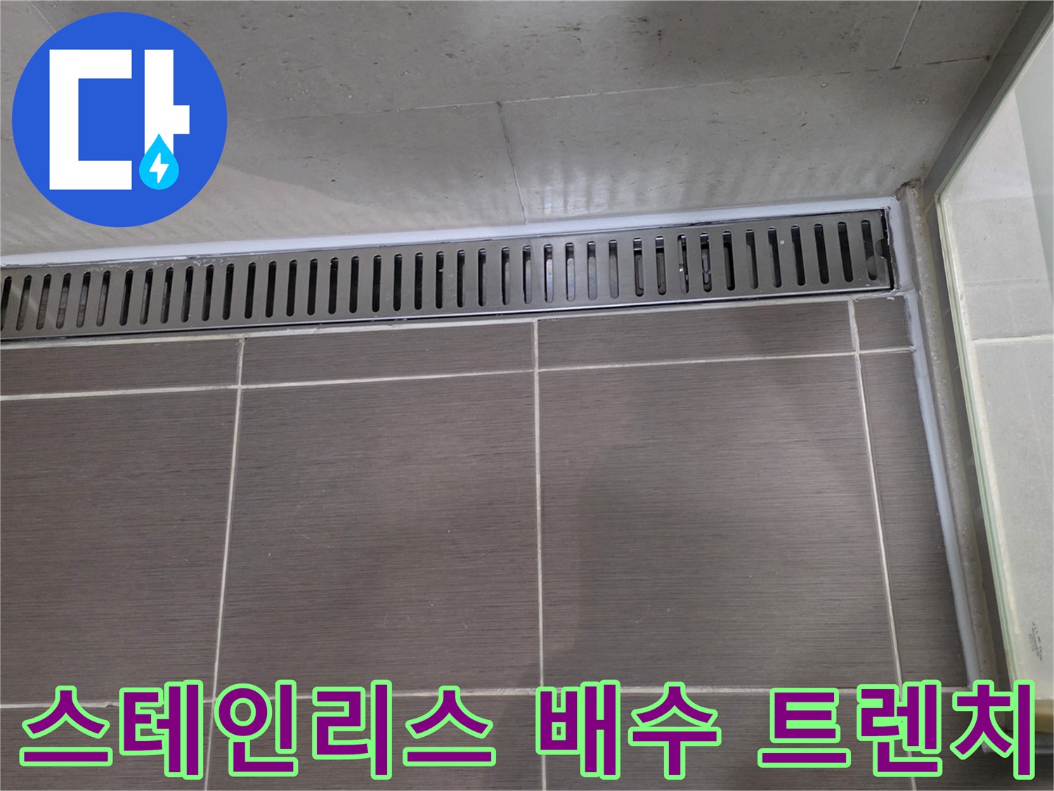 욕실 바닥에 설치된 금속 재질의 배수 트렌치와 타일 마감