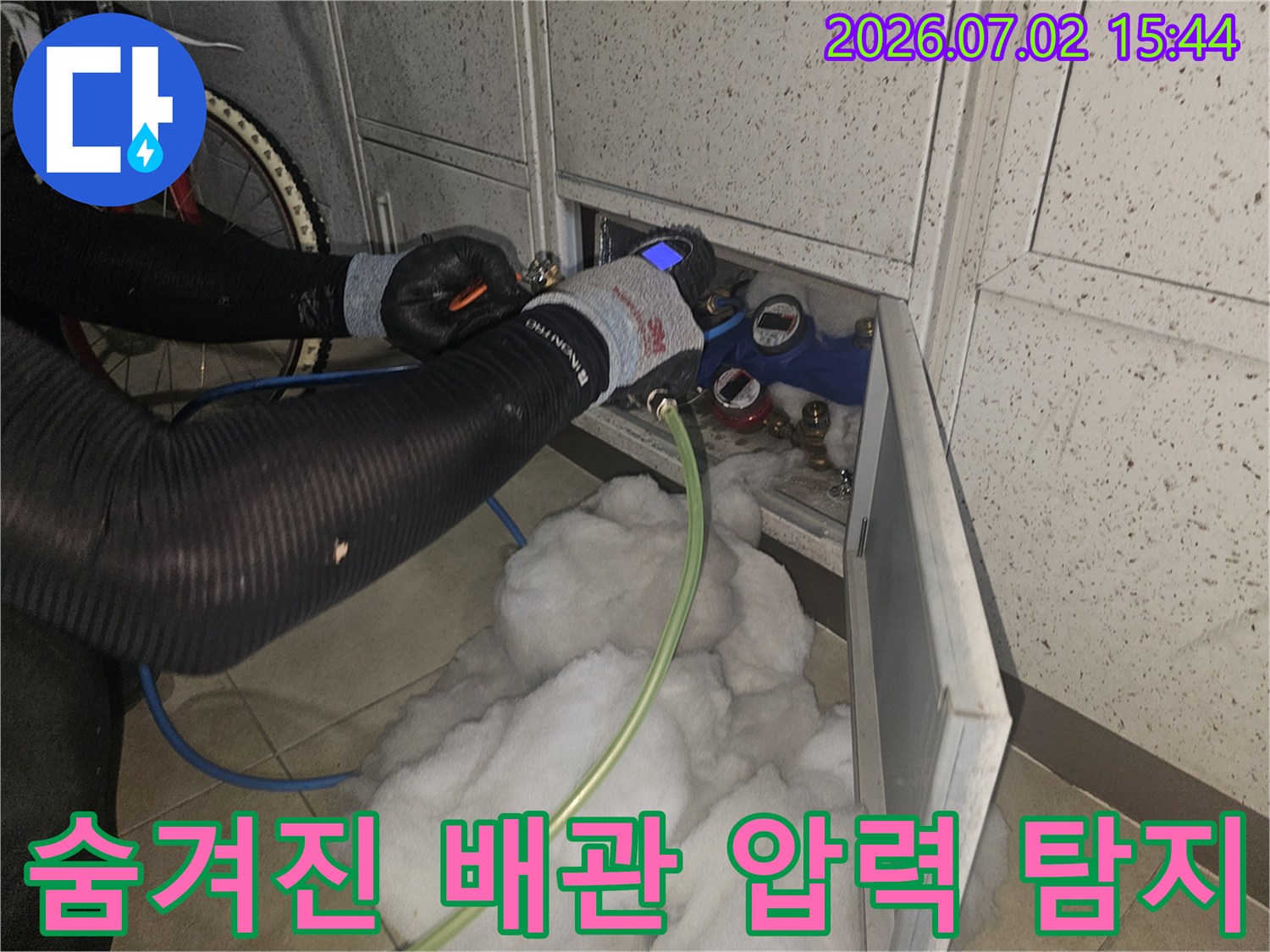 누수-전문가가-숨겨진-배관의-누수-지점을-찾기-위해-정밀-압력-측정-장비를-연결하여-탐지하는-모습