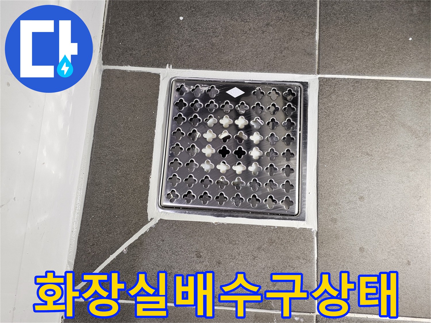 어두운색 타일로 마감된 화장실 배수구 주변 모습입니다.