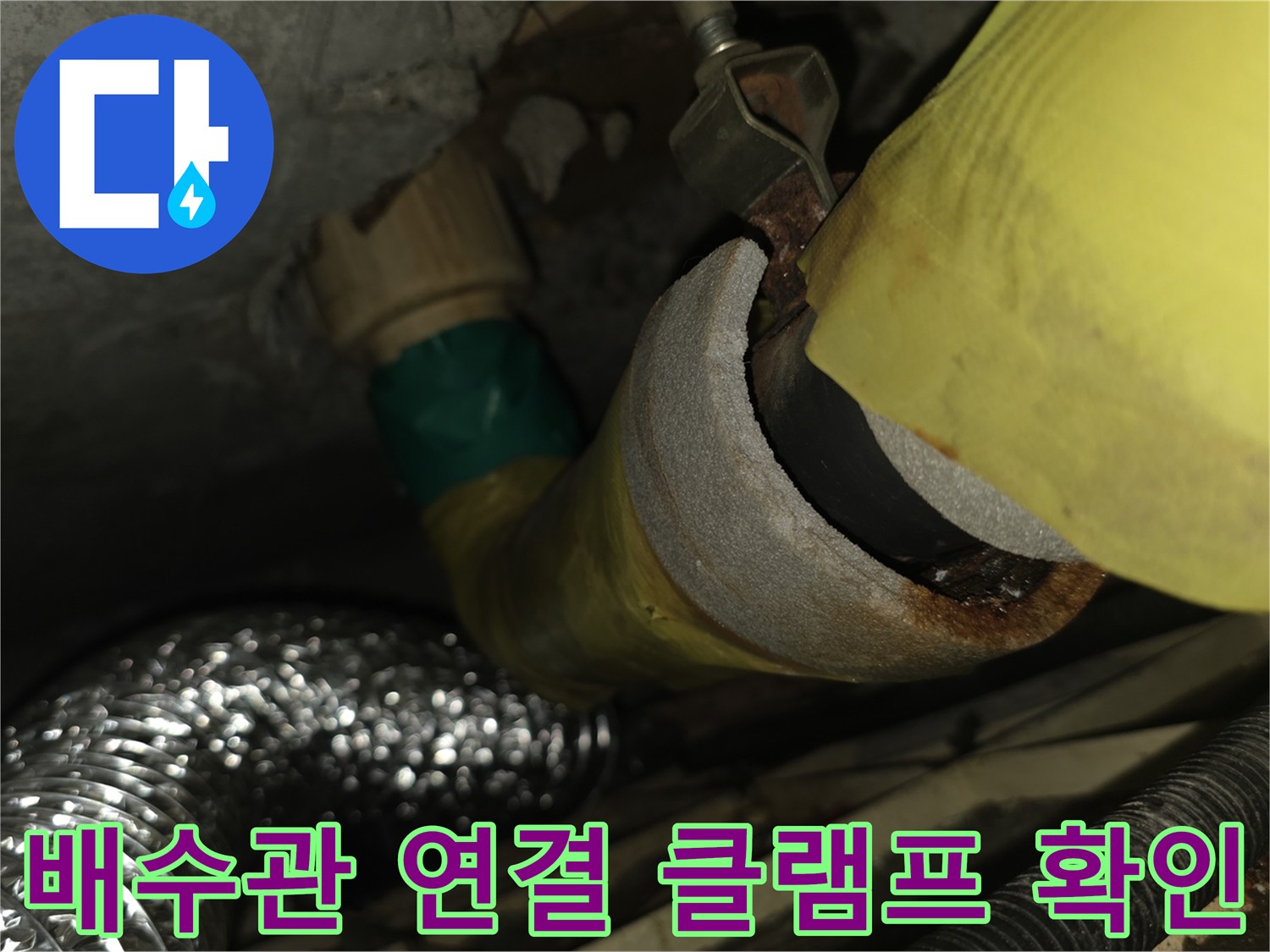 노란색 보온재로 감싸진 배관의 금속 고정 장치를 근접 촬영한 사진입니다.