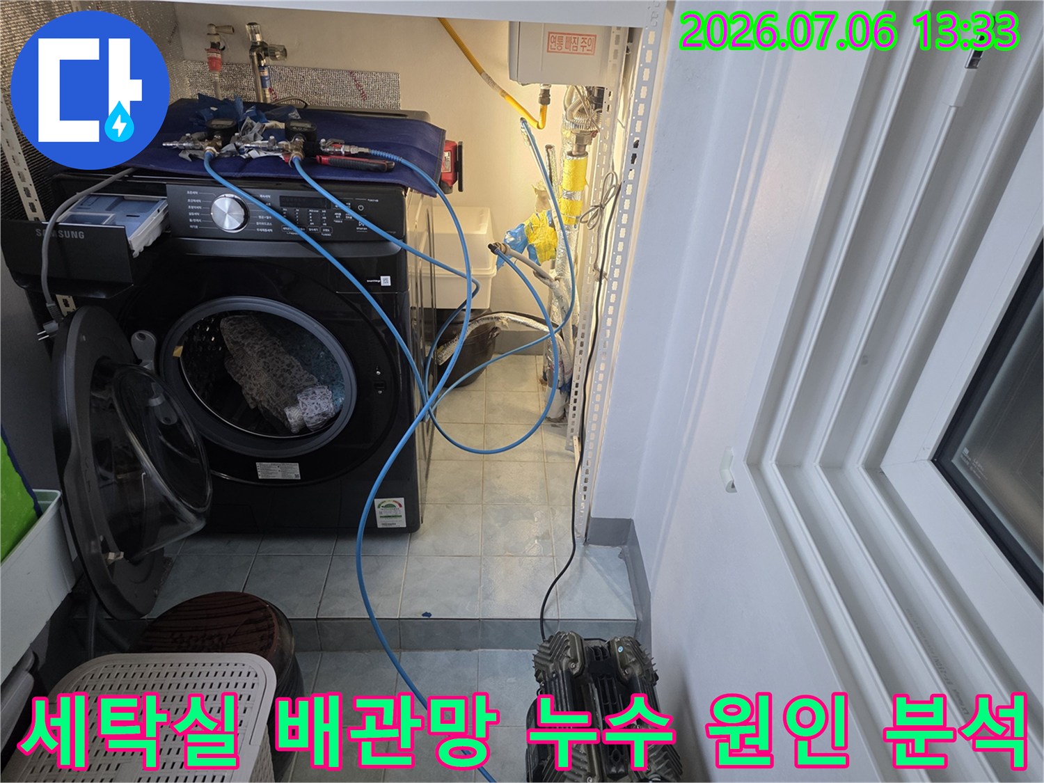 세탁기 옆으로 노출된 복잡한 수도 배관을 따라가며 점검하는 전문가의 모습