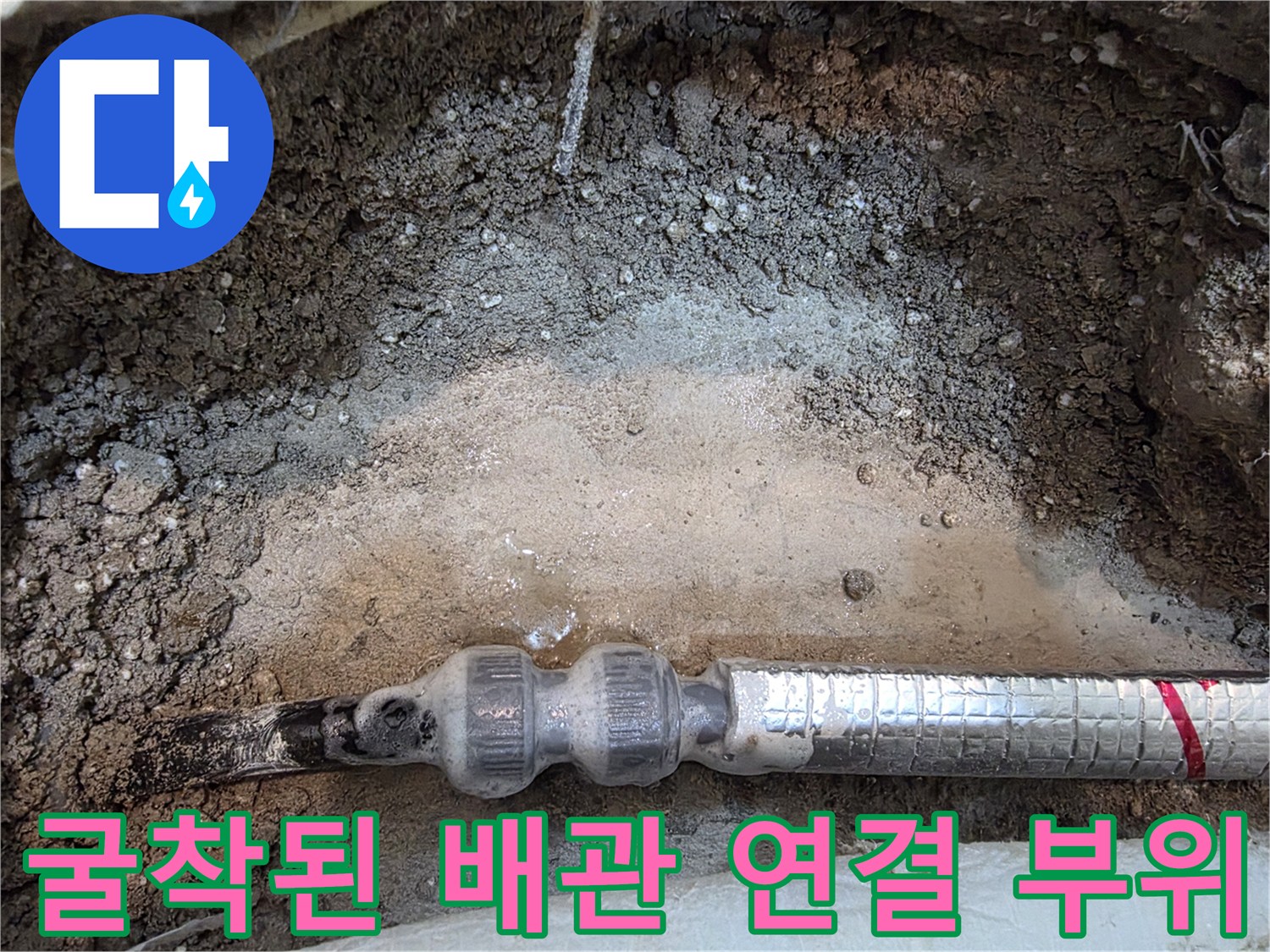 콘크리트 층 아래 노출된 은박 보온재 배관의 상태를 보여주는 사진입니다.