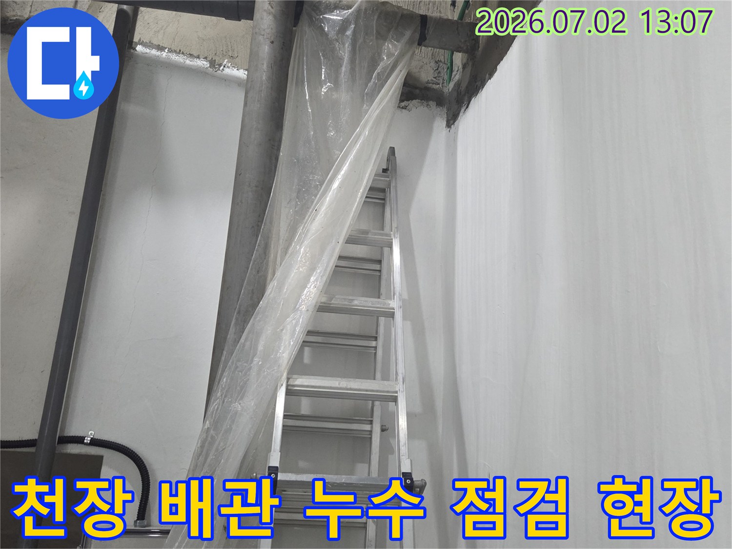 회색빛 지하 천장에 설치된 복잡한 하수 배관과 작업용 사다리 사진