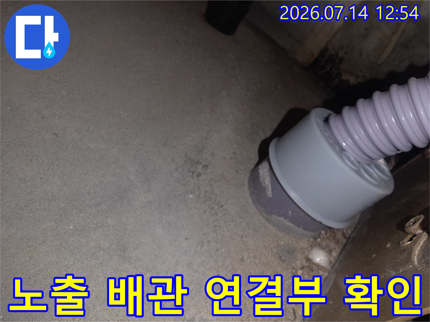 싱크대 아래 설치된 회색 소켓과 유연한 주름형 호스의 결합 부위