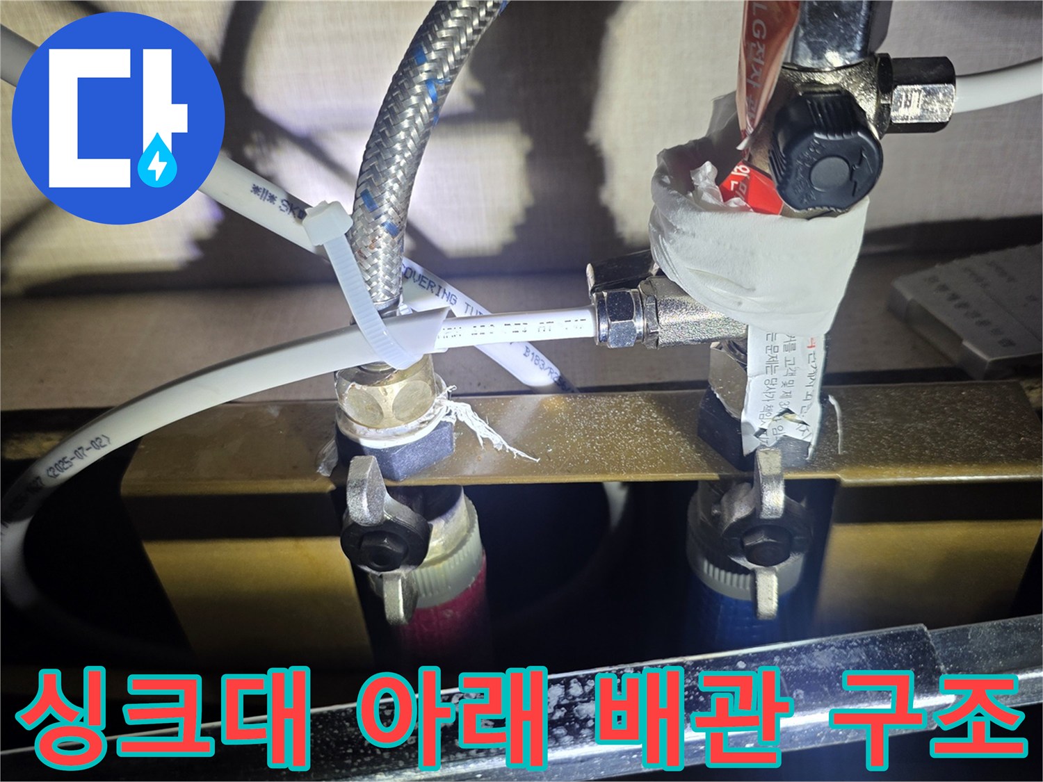 싱크대 하단 밸브와 금속 호스의 연결 상태를 보여주는 근접 사진입니다.