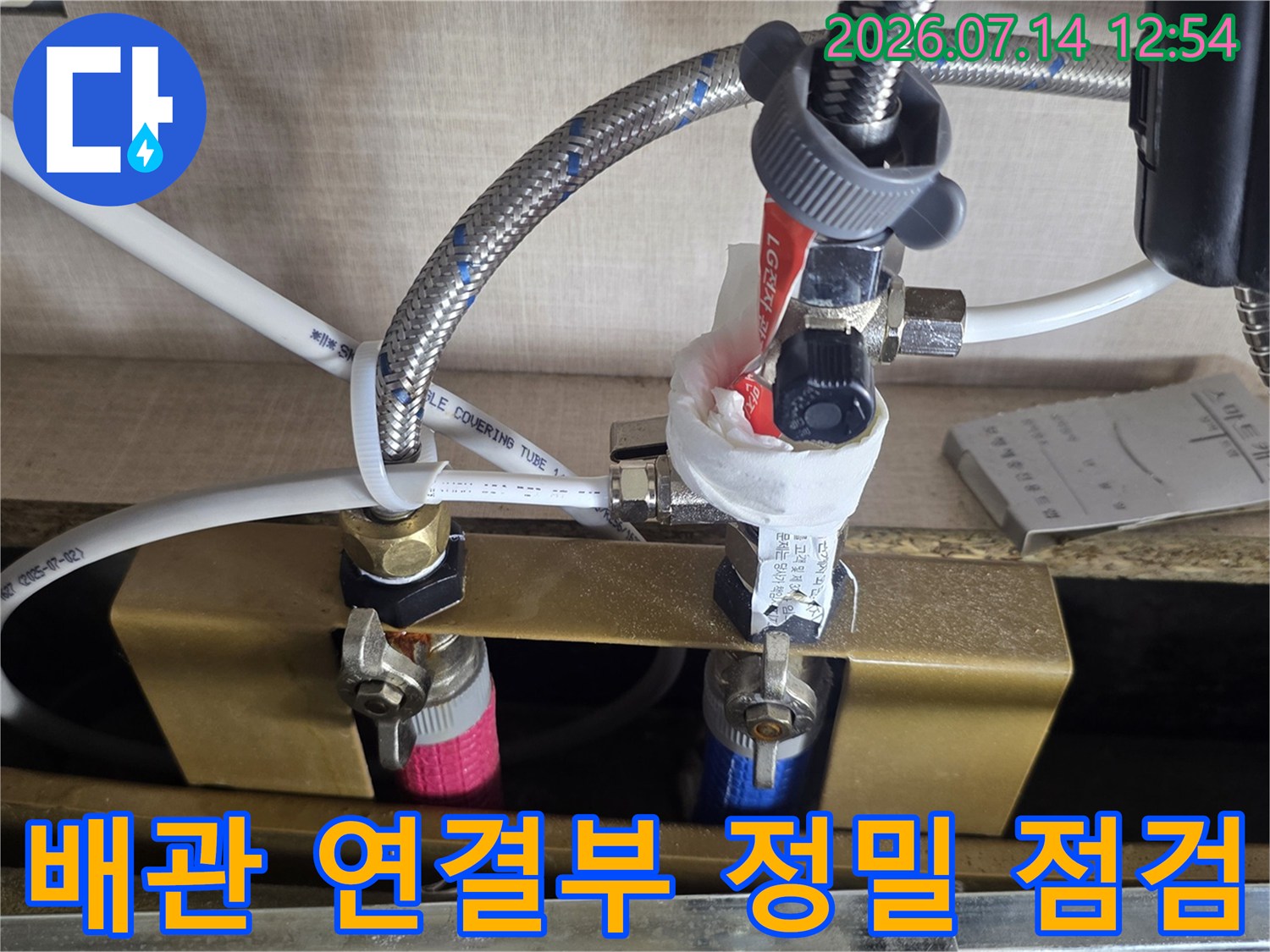 싱크대 하부의 노출 배관에 압력계와 호스를 연결하여 누수 여부를 진단하는 장면