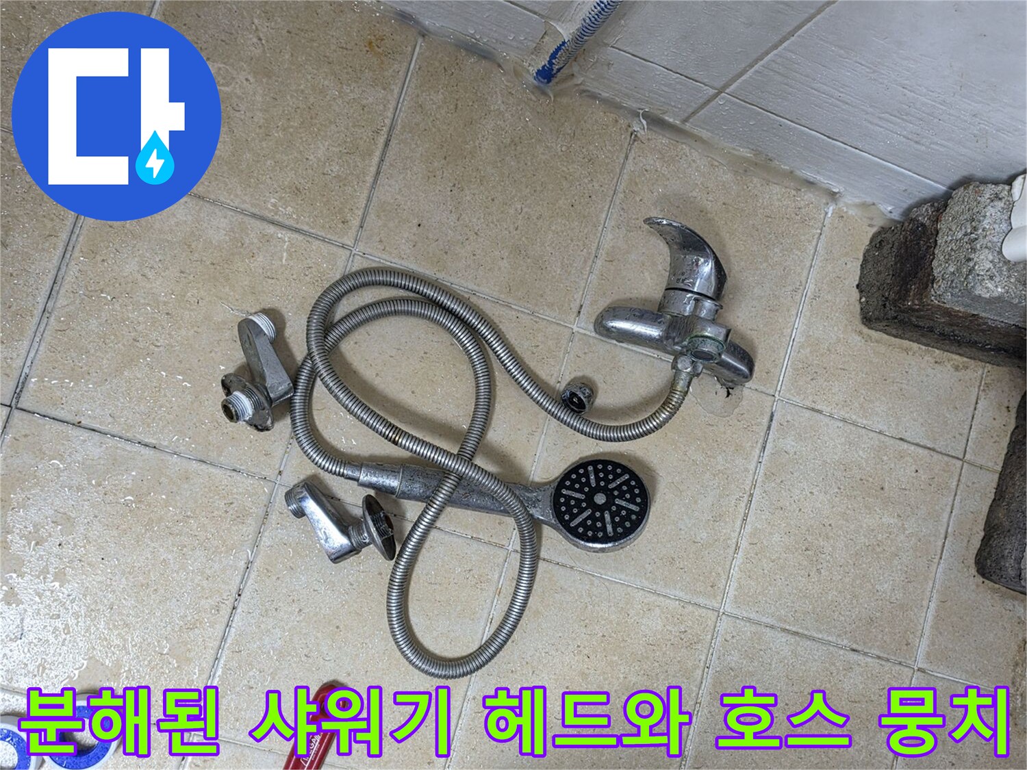 바닥 타일 위에 분리되어 놓인 샤워기 부품과 공구