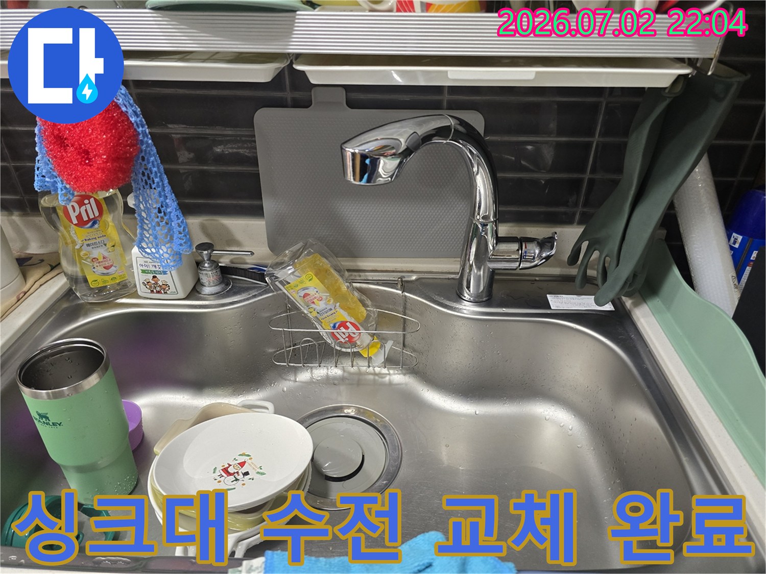 새로 교체된 스테인리스 재질의 주방 싱크대 수전과 세척용품이 놓인 배수구 모습