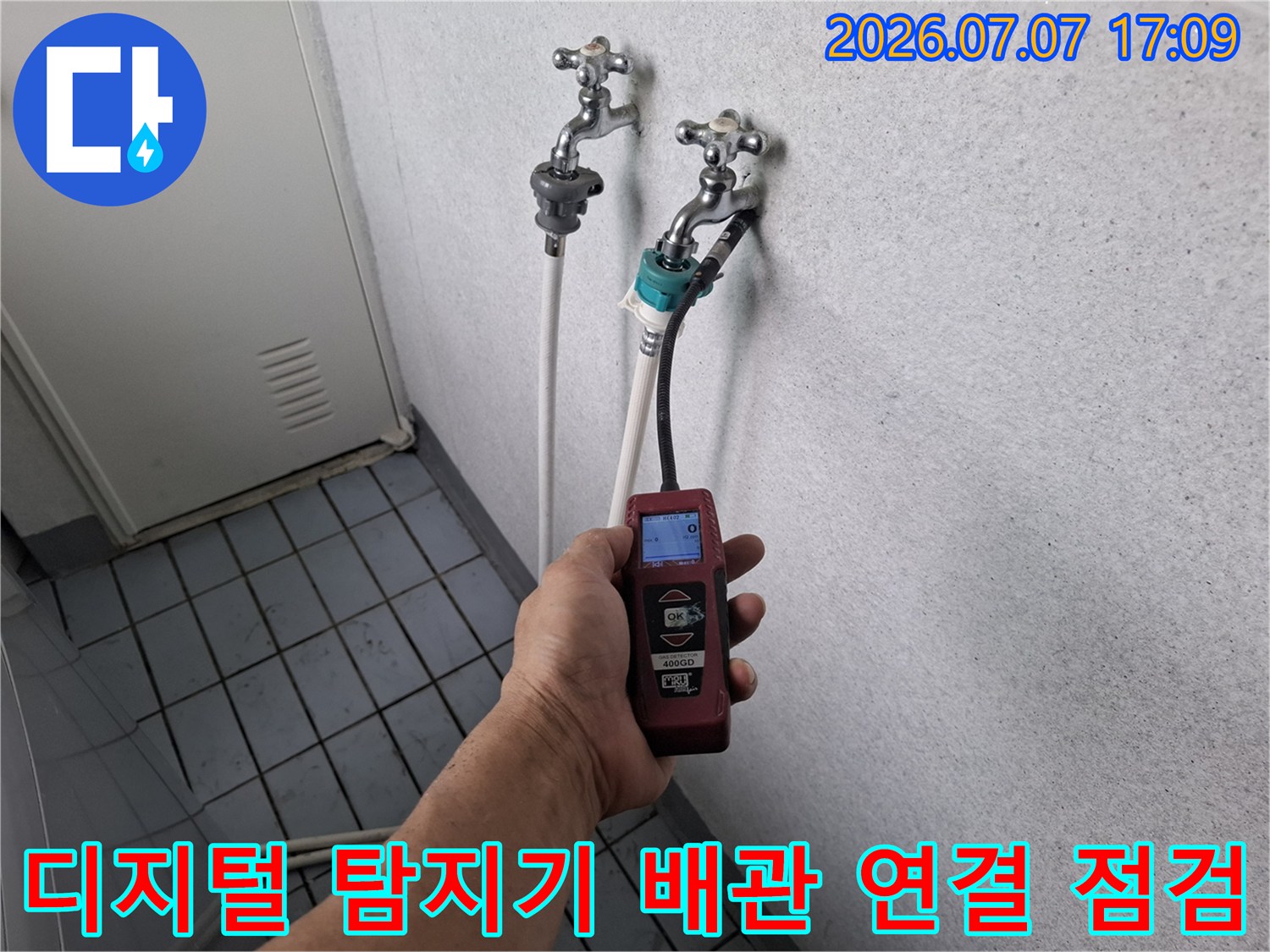 베란다 위치의 노출된 배관에 측정 기기를 연결하여 누수 여부를 실시간 데이터로 확인하는 모습