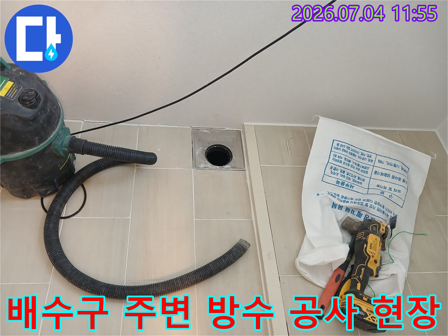 먼지 흡입기와 전동 드릴이 비치된 세탁실 배수구 보수 현장