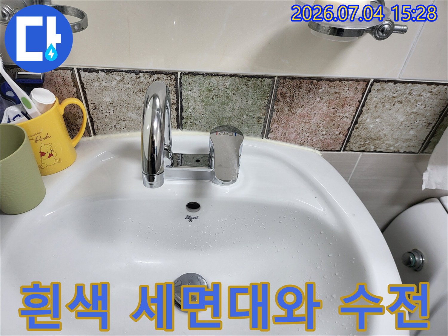하얀색 세면대 위에 설치된 크롬 소재의 수도 수전과 주변 타일 마감