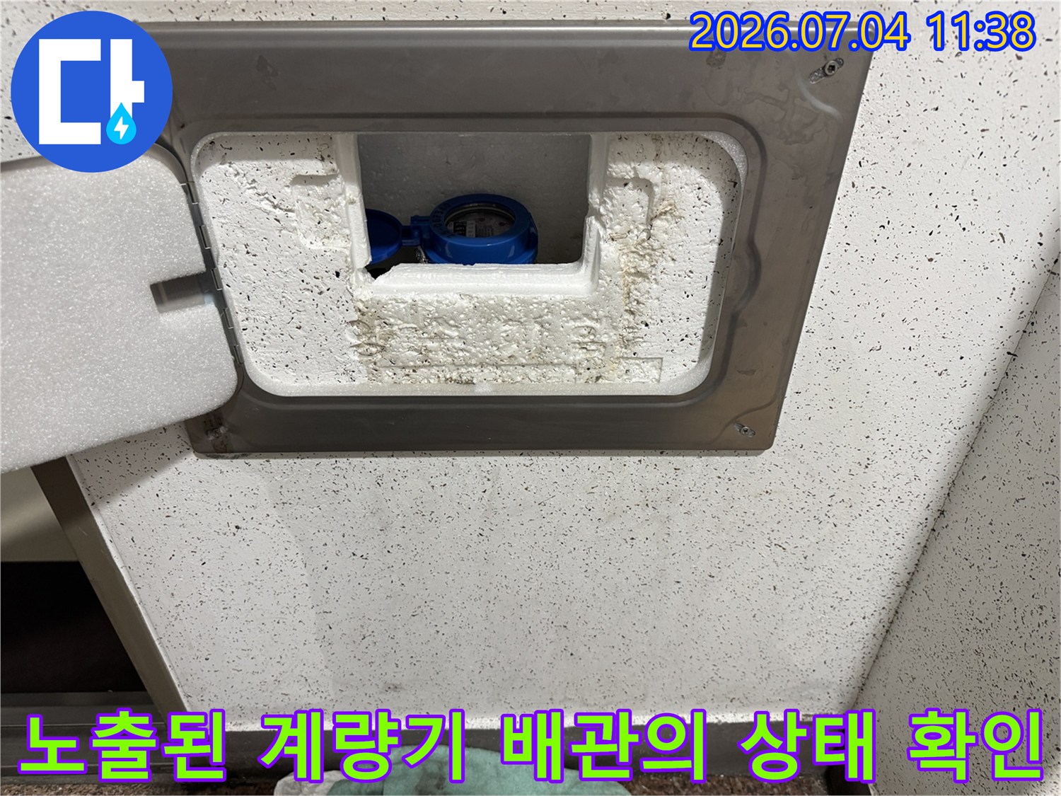 흰색 마감재와 파란색 밸브가 있는 수도계량기 내부 점검 장면
