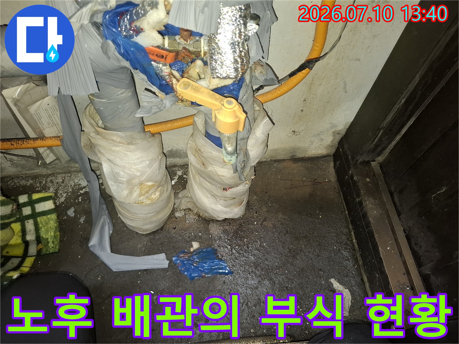 보온재가 덮인 상태에서 드러난 부식된 금속 배관과 연결부