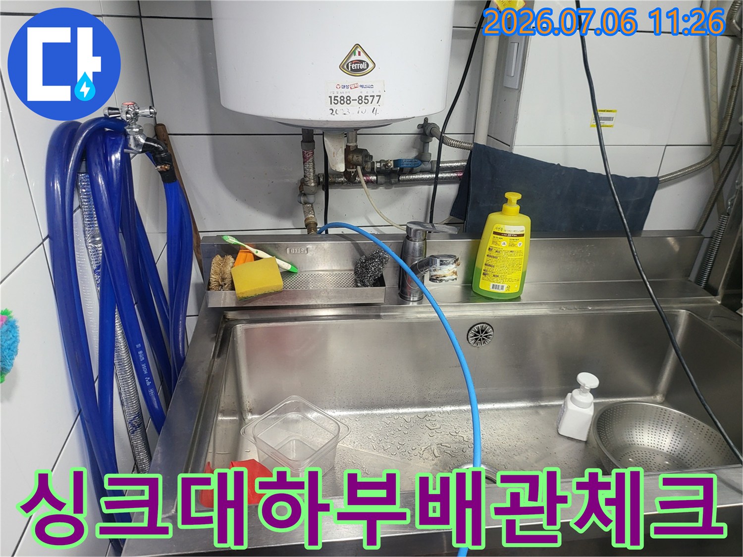 주방 싱크대 밑에 설치된 배관과 파란색 테스트 호스 연결 모습