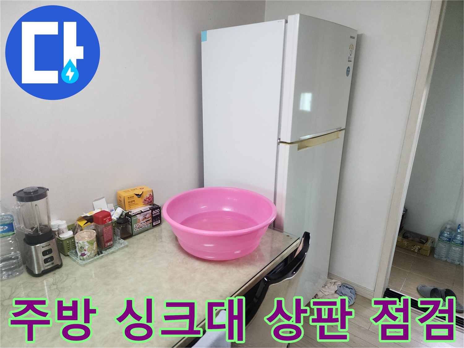 냉장고 옆 싱크대 주변의 물건들과 대야가 놓여 있는 모습입니다.