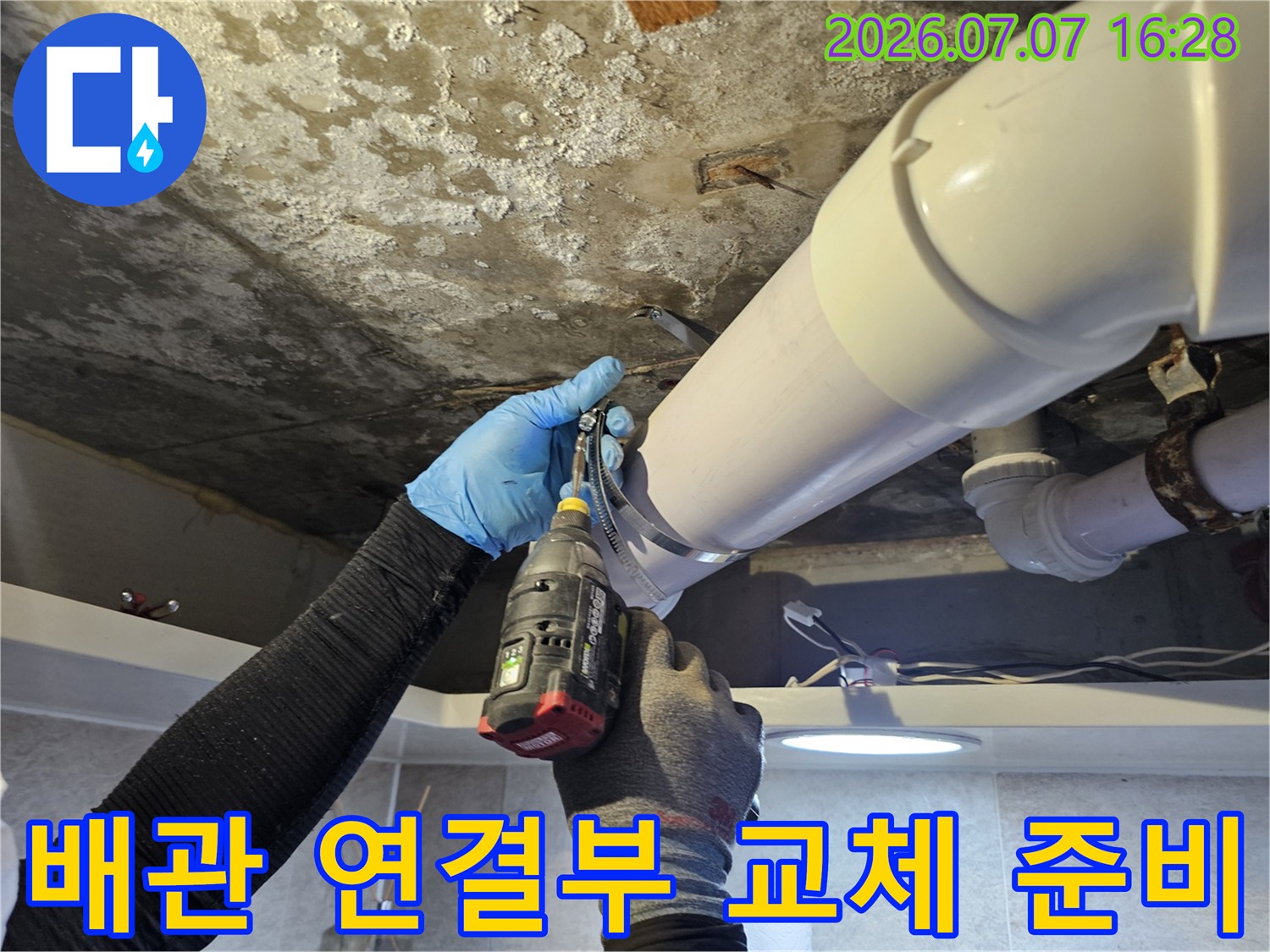 장갑을 낀 작업자가 화장실 천장 안쪽 배관 노후 부위를 분해하며 수리 준비를 하는 모습