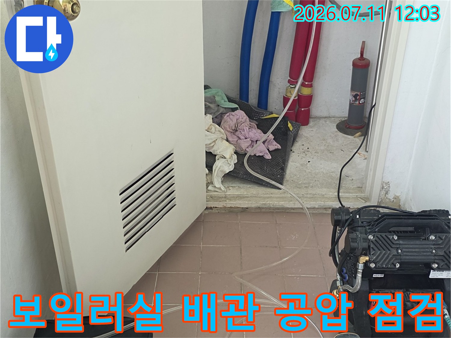 보일러실 내부에 연결된 빨간색과 파란색 배관에 압력 게이지를 연결하여 누수 여부를 확인하는 장면