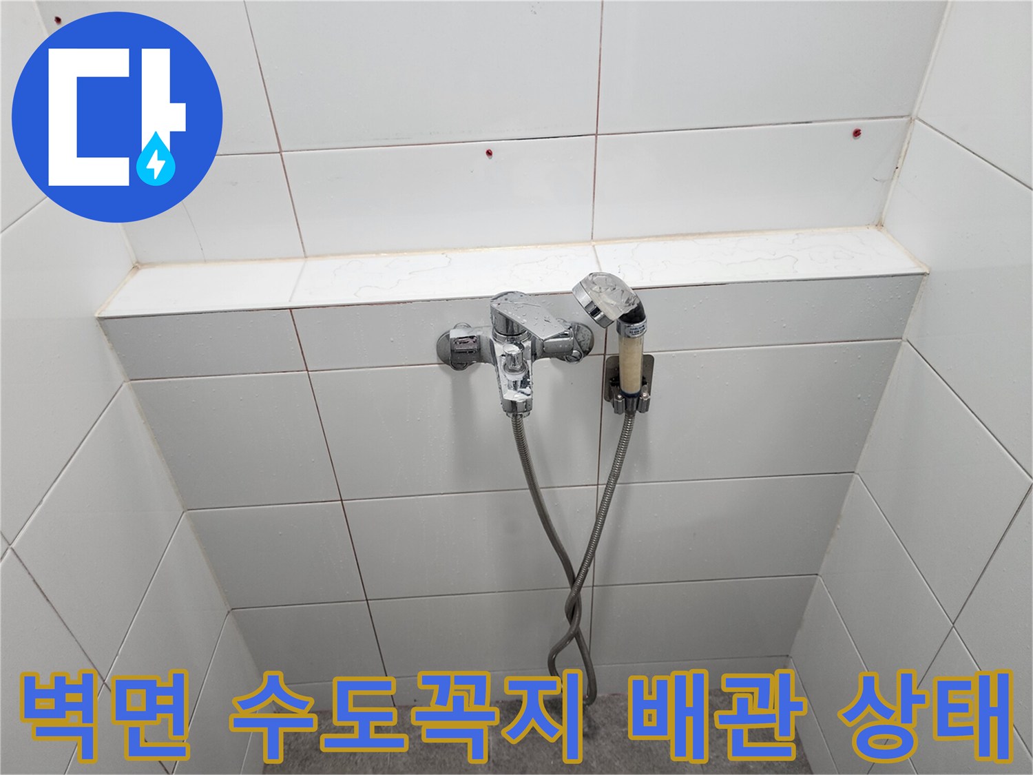 화장실 벽면에 설치된 은색 수전과 샤워 호스 연결 부위 사진