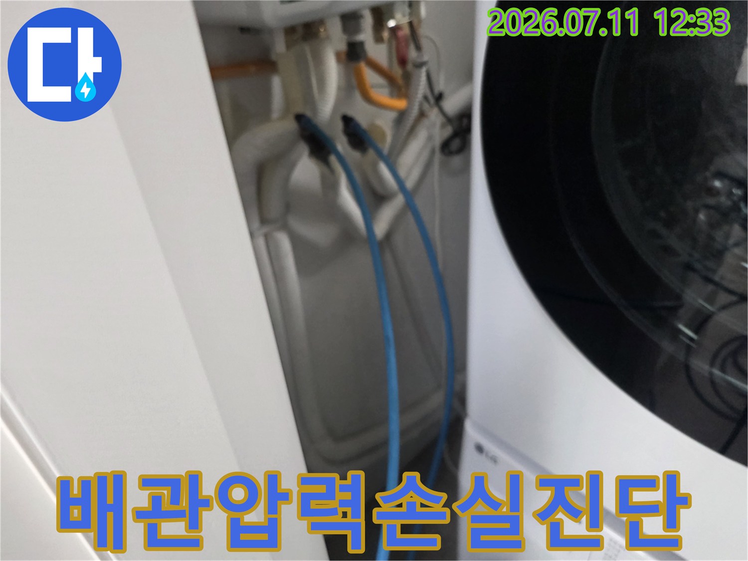 세탁기 옆 공간에 위치한 배관과 연결된 호스를 통해 공압 검사를 진행하는 모습