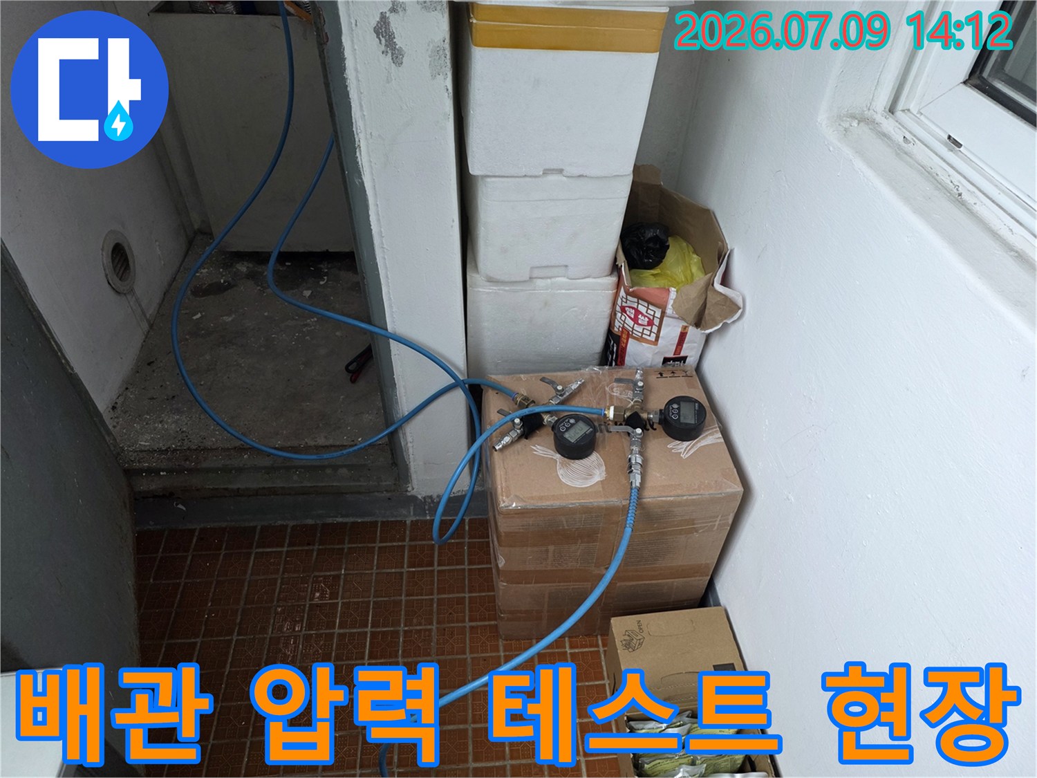 화장실 내 설치된 배관에 연결된 파란색 호스와 측정 장비