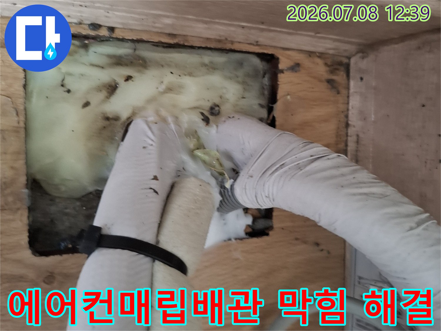 백색 보호재로 감싸진 에어컨 배관을 전문 장비로 세척하는 모습