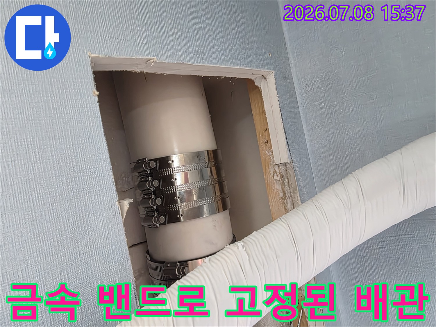 안전하게 고정된 에어컨 드레인 파이프와 마감재가 입혀진 외벽 배수부의 근접 촬영 사진