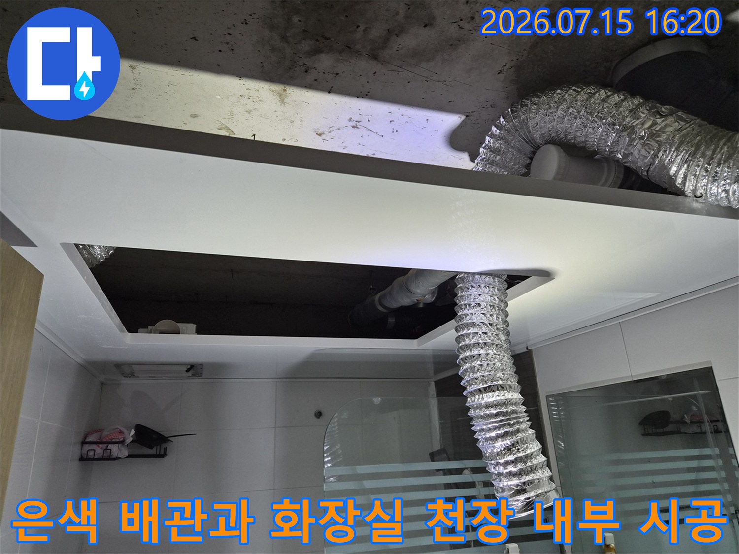 화장실 천장 안쪽의 은색 단열재로 감싼 배관과 환풍구 설치 장면
