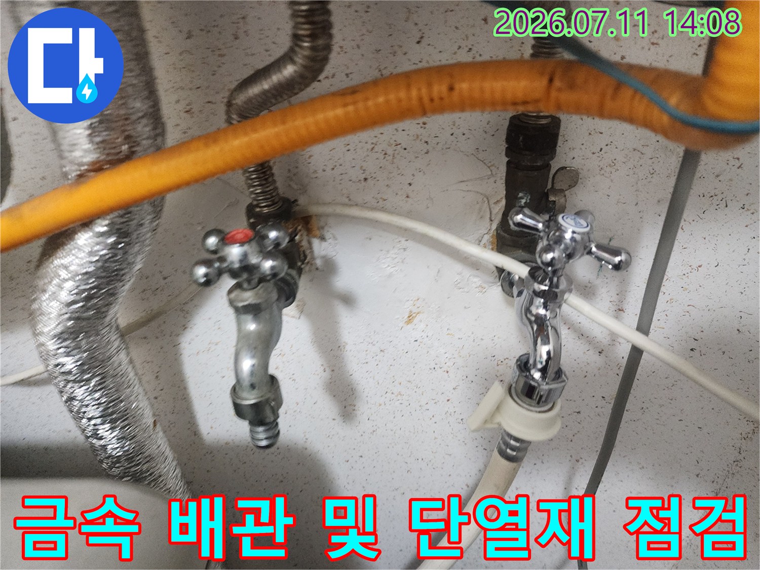 천장 내부의 금속성 밸브와 주황색 보온재로 감싸진 수도배관 구조