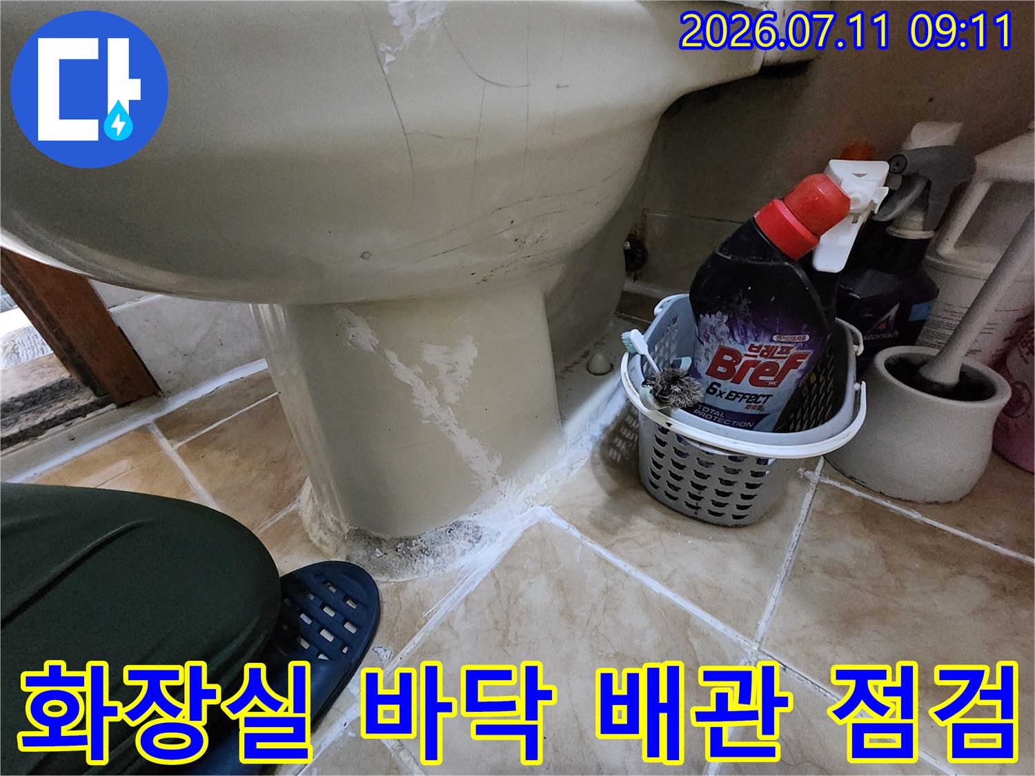 욕실 세면대 아래쪽 노출된 파이프라인과 타일 경계의 수분 상태를 체크하는 장면