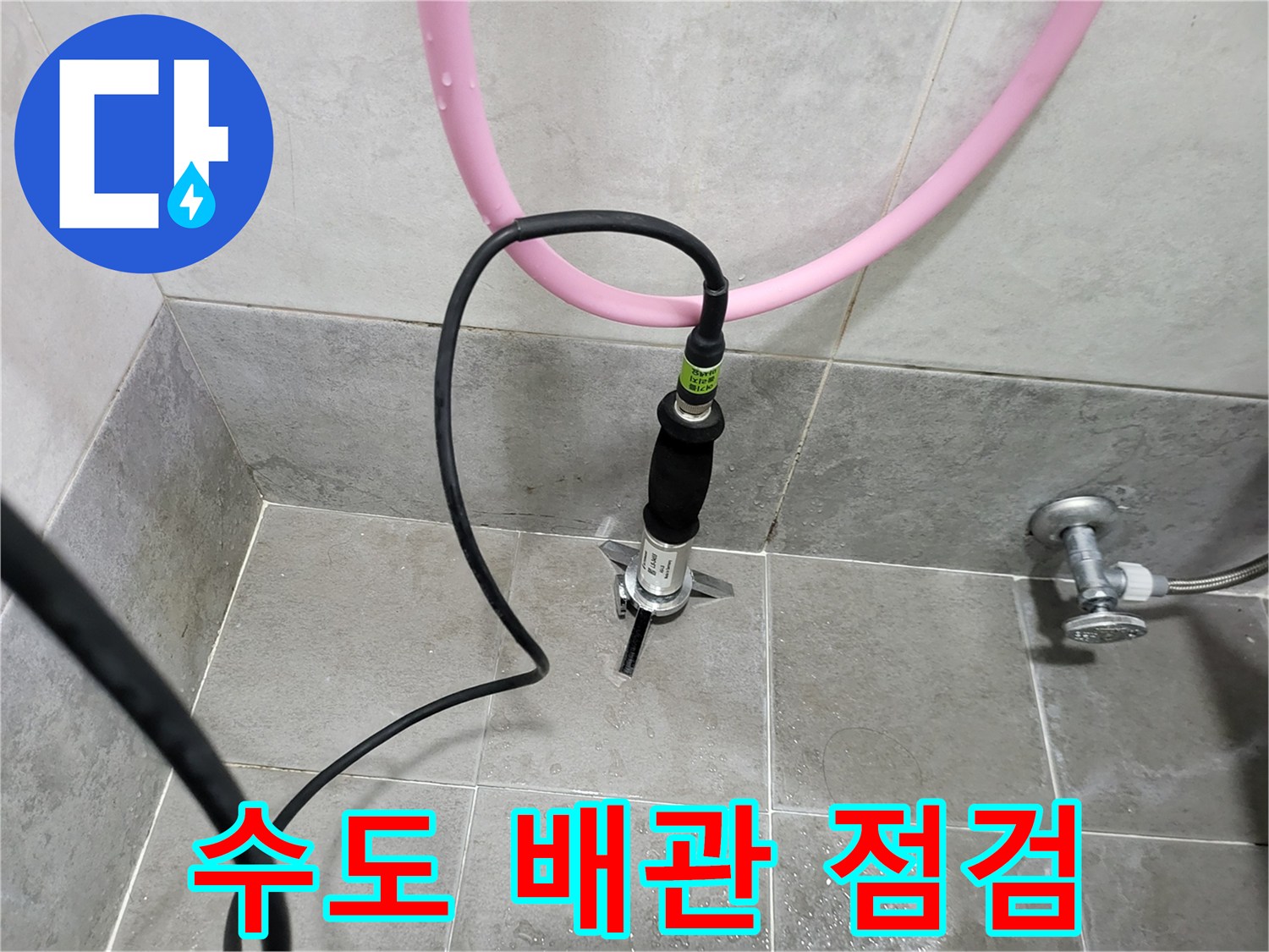 바닥 타일 사이로 노출된 배관 연결 부위에 압력계가 설치되어 있습니다.