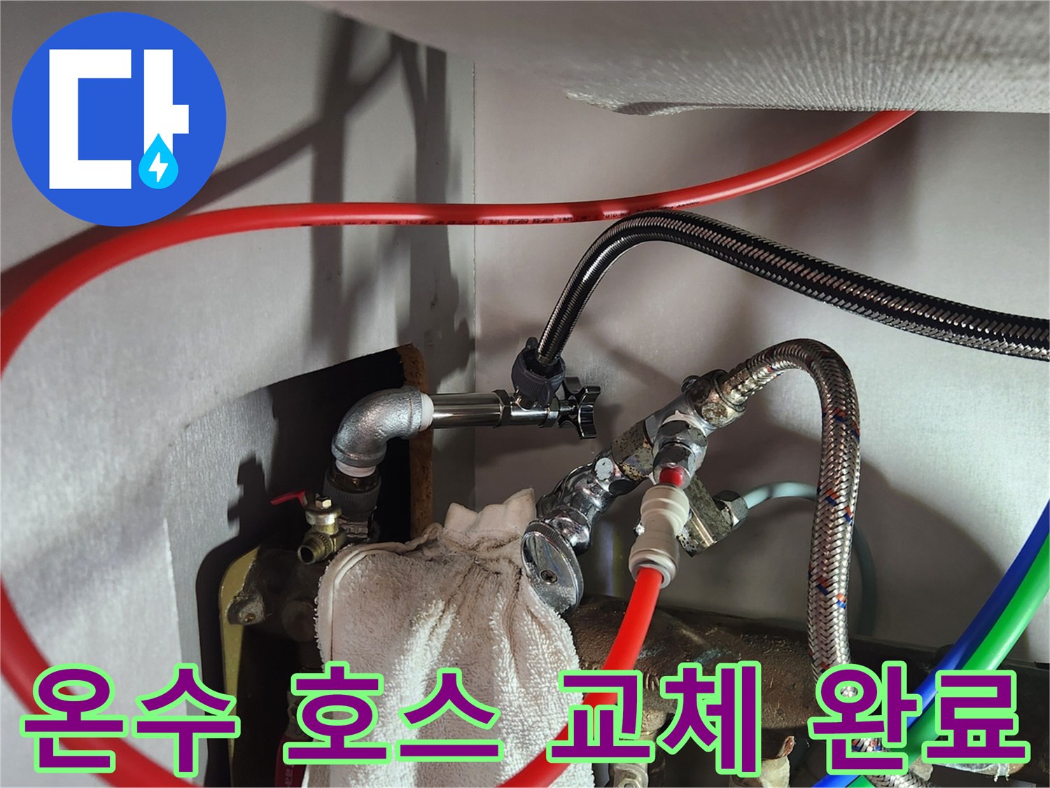 새로 설치된 은색 고압 호스와 붉은색 온수 배관의 연결 상태를 보여주는 사진입니다