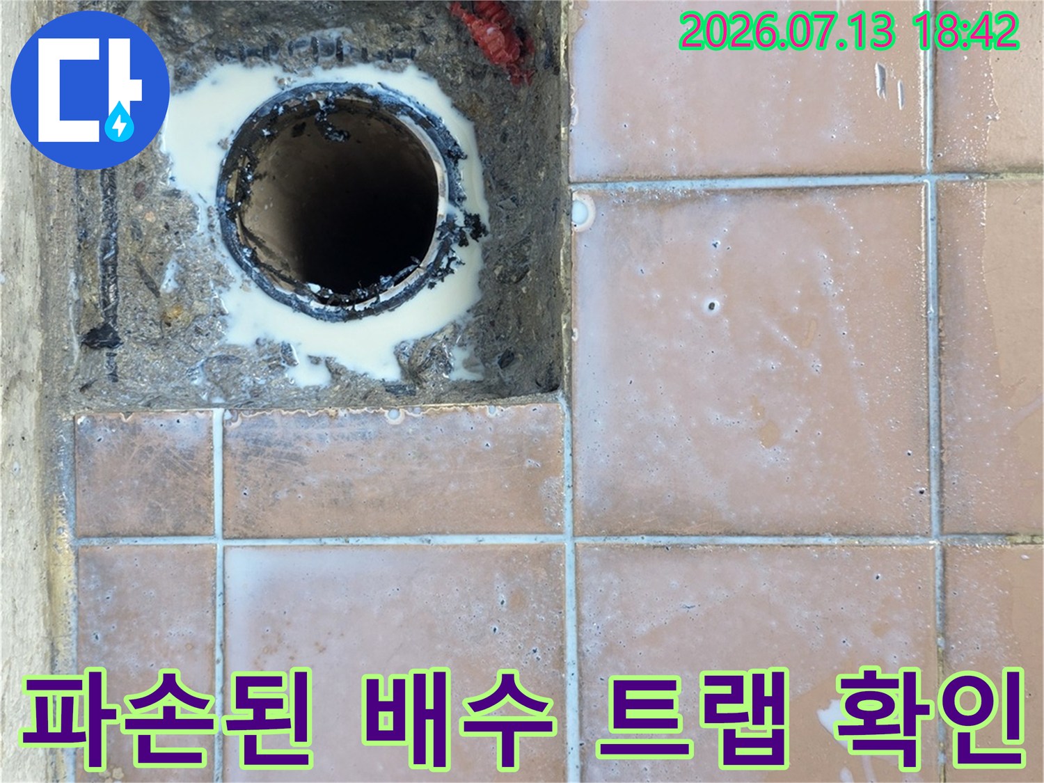 노출된 배관과 주변 타일의 파손 상태를 촬영한 세탁실 배수구 모습