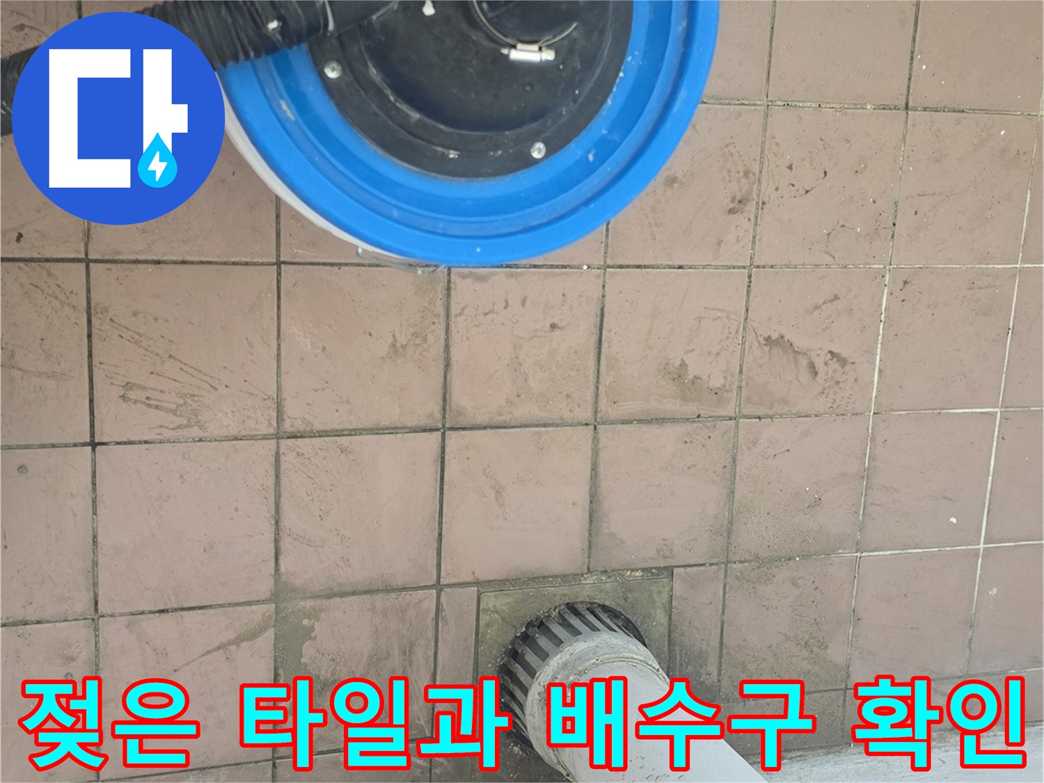 배수구 주변의 젖은 바닥 타일과 작업용 진공 장치
