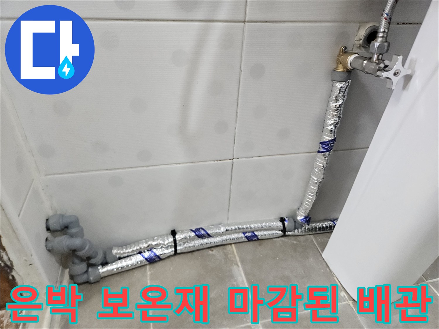 욕실 벽면 하단에 설치된 은박 보온재로 감싸진 신규 직수 배관