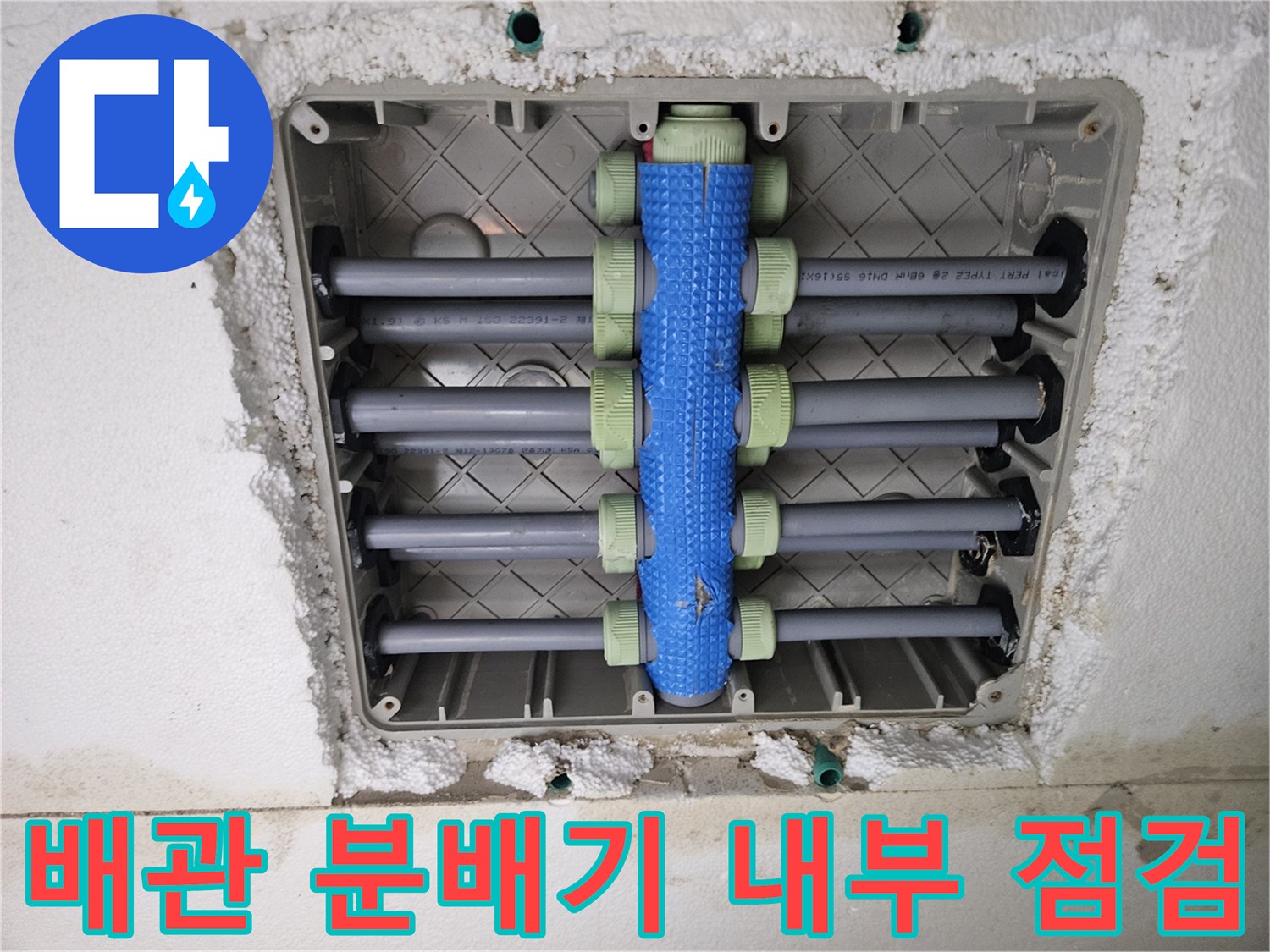 세탁실 바닥 매립 부위의 배관 분배기 및 연결 부속을 촬영한 사진입니다.