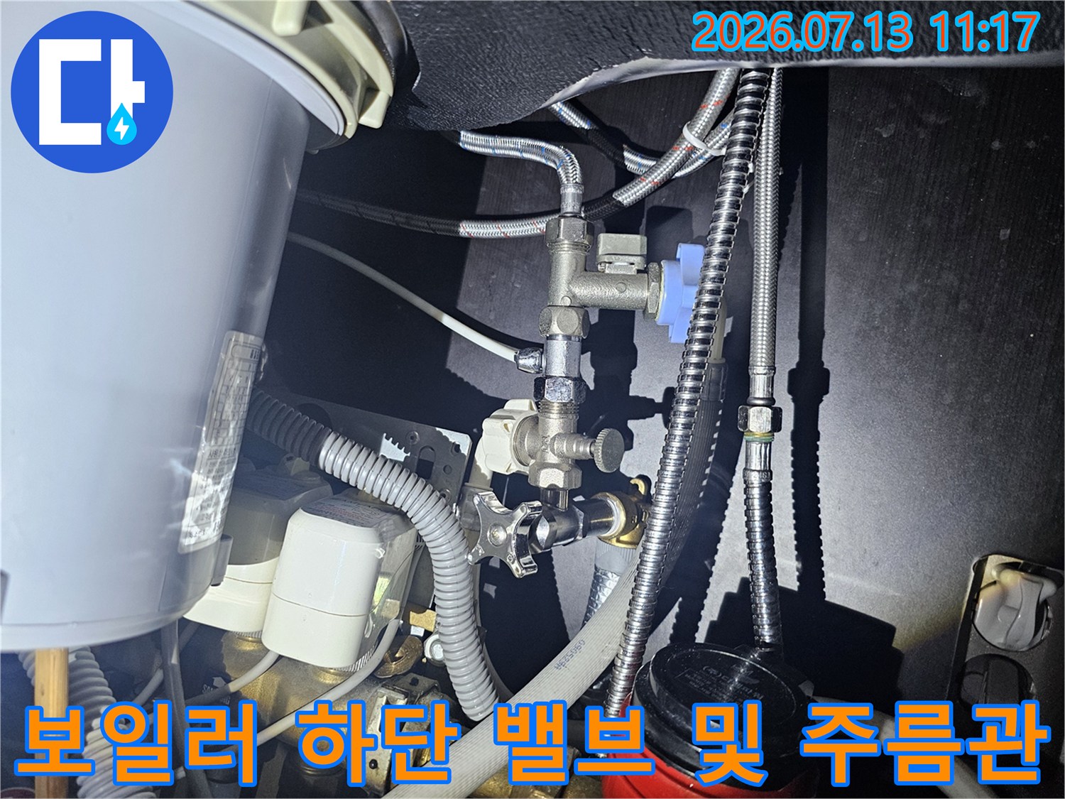 금속 배관과 유연한 은색 주름관이 연결된 보일러 내부-하단부